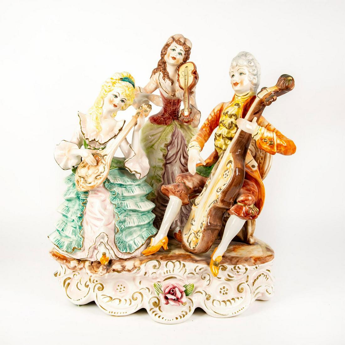 Large Capodimonte Style Figure Group, Musical Trio: Hand painted polychrome statuette. Includes cellist, mandolinist and violinist. Seated musicians performing. Mounted on footed base. Marked Capodimonte on the underside,. Broken flowers. Issued: 20th