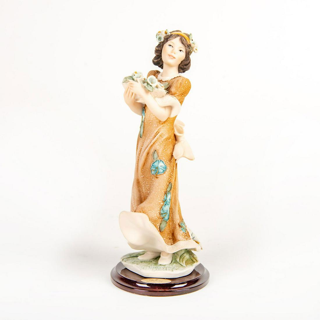 Florence Giuseppe Armani Lady Figurine, Purity 1426C: Wearing flowing orange dress; girl holding basket of flowers in both hands. Signed Giuseppe Armani; mounted on circular wooden base. Artist: Giuseppe Armani Issued: c. 1999 Dimensions: 9.75"H Manufact