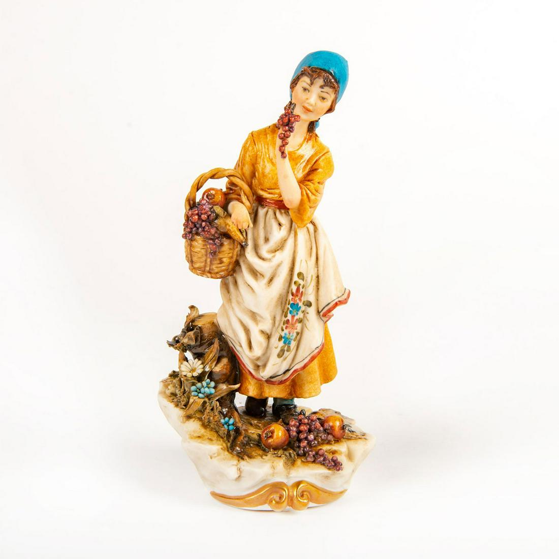 Capodimonte Scapinello Porcelain Figurine, Peasant Girl: Orange and blue colorway; girl holding basket of fruits. Signed Scapinello. Crown over N mark on base. Artist: W. Scapinello Issued: 20th c. Dimensions: 6.75"H Manufacturer: Capodimonte Country of Ori