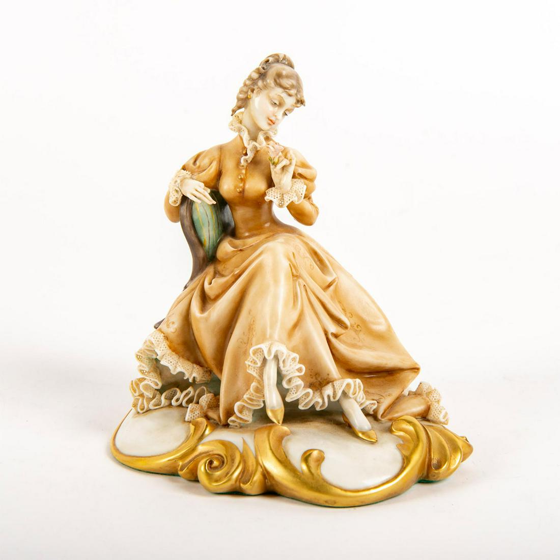 Antonio Borsato Porcelain Lace Figural Group, Seated: Hand painted on rococo style gilded base depicting a seated lady holding a pink rose. Antonio Borsato Made In Italy red mark to bottom base with original paper label. Green felt. Missing lace netting.