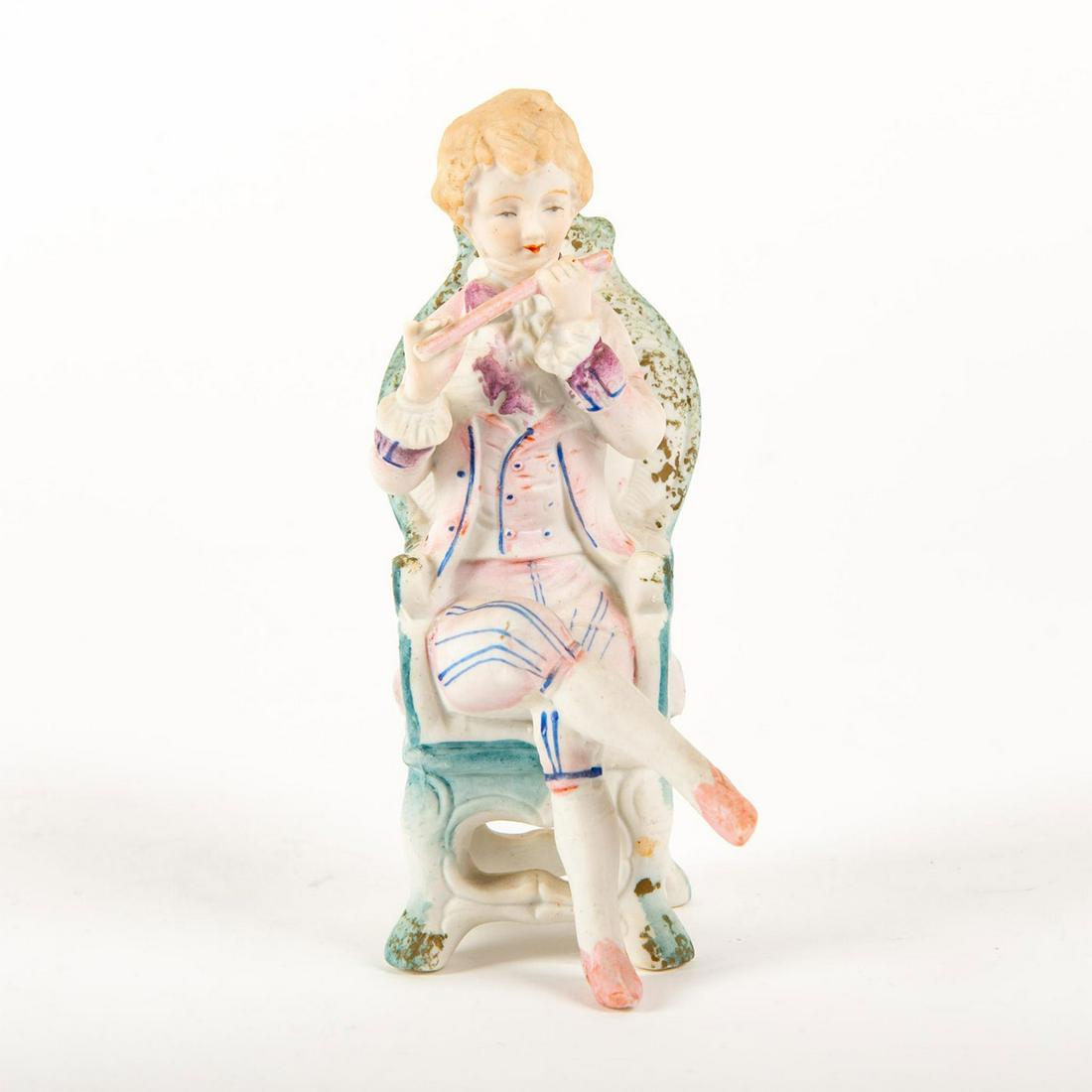 Fern Japanese Ceramic Figurine, Seated Boy With Flute: Hand painted, depicting a seated boy in pink playing the flute; matte finish. Impressed Copyright c. L& Minc and original foil label to backside of chair. Issued: 20th c. Dimensions: 6.5"H Manufacture