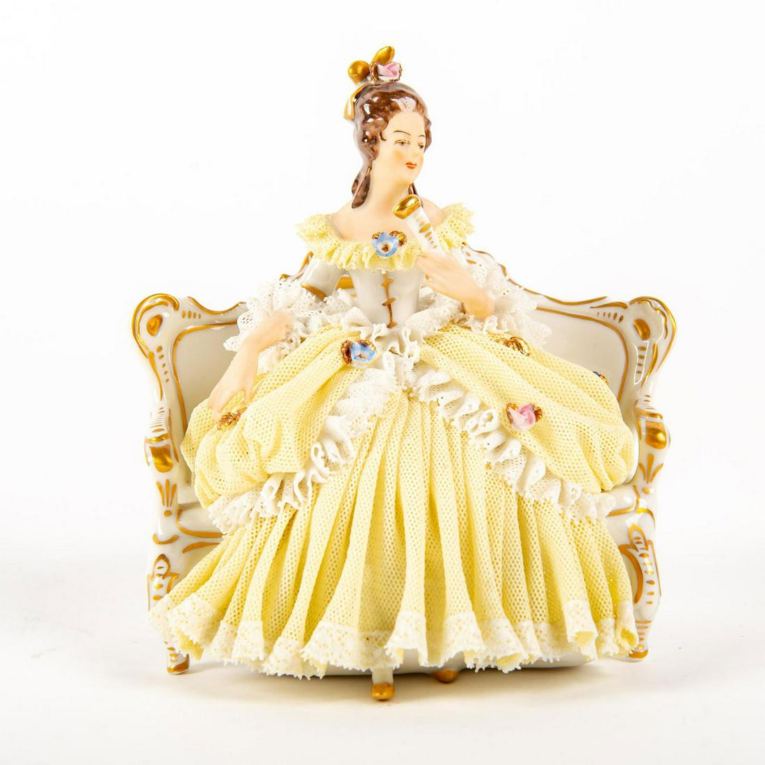 German Porcelain Lace Figural Group, Lady Seated In: Features a lady seated in a rococo style chair in yellow gown trimmed in lace netting with applied flowers. Hand painted with accents of gold gilt. Marked Made In Germany to bottom base. Issued: 20th 