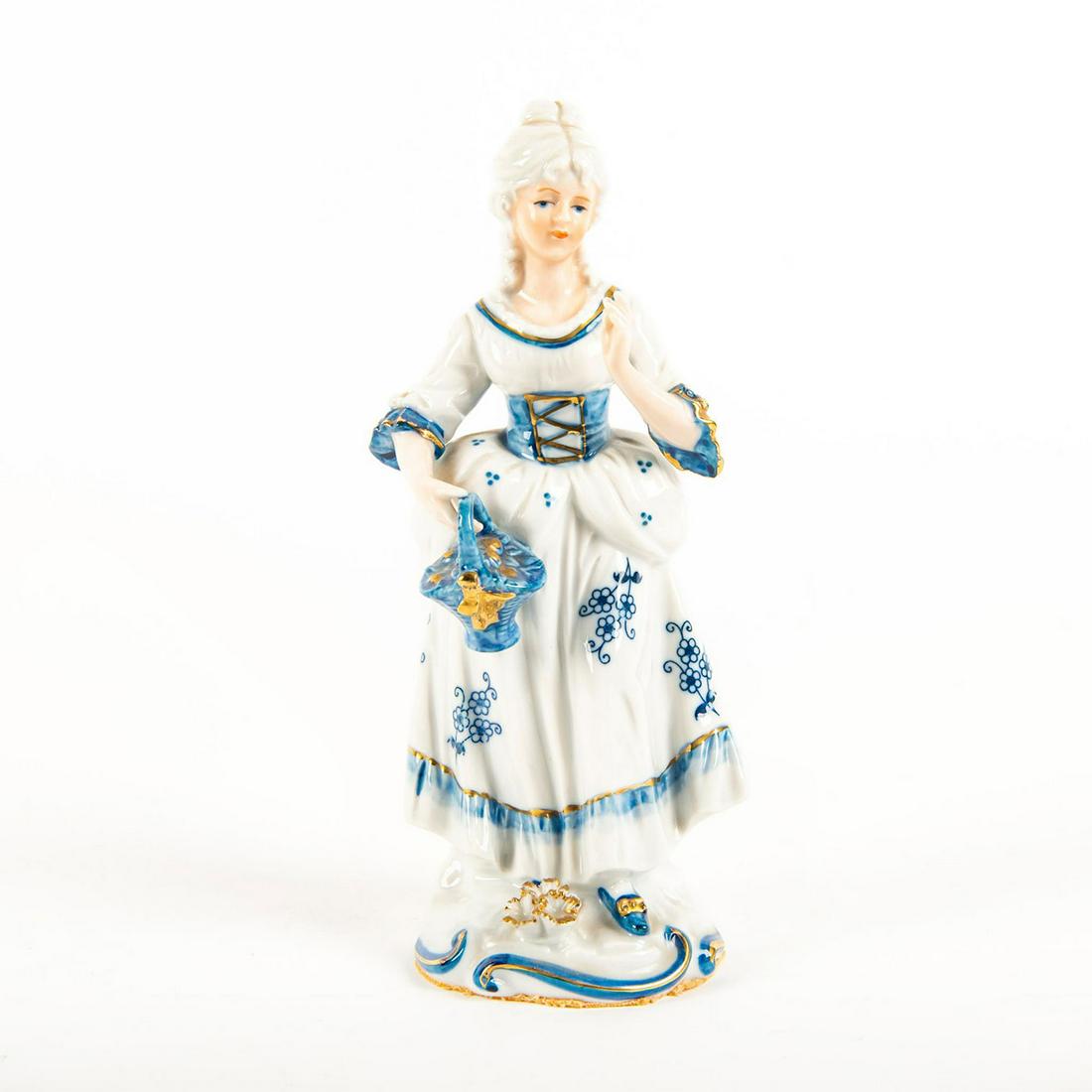Porcelain Flow Blue Figurine, Victorian Woman: In style of KPM, glazed with accents of gold gilt. Felt to bottom base. Unmarked. On rococo style base depicting a Victorian woman holding a blue basket. Issued: 20th c. Dimensions: 9"H