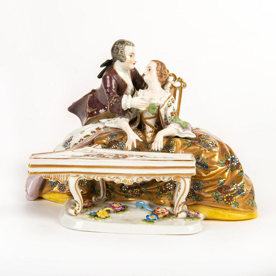 Vintage Ludwigsburg Figural Group, Couple By Piano: Heavily gilded figure; painted floral pattern. Woman playing the piano; man stands by her. Ludwigsburg backstamp. Man has broken fingers. Issued: 20th c. Dimensions: 6"H Manufacturer: Ludwigsburg Coun