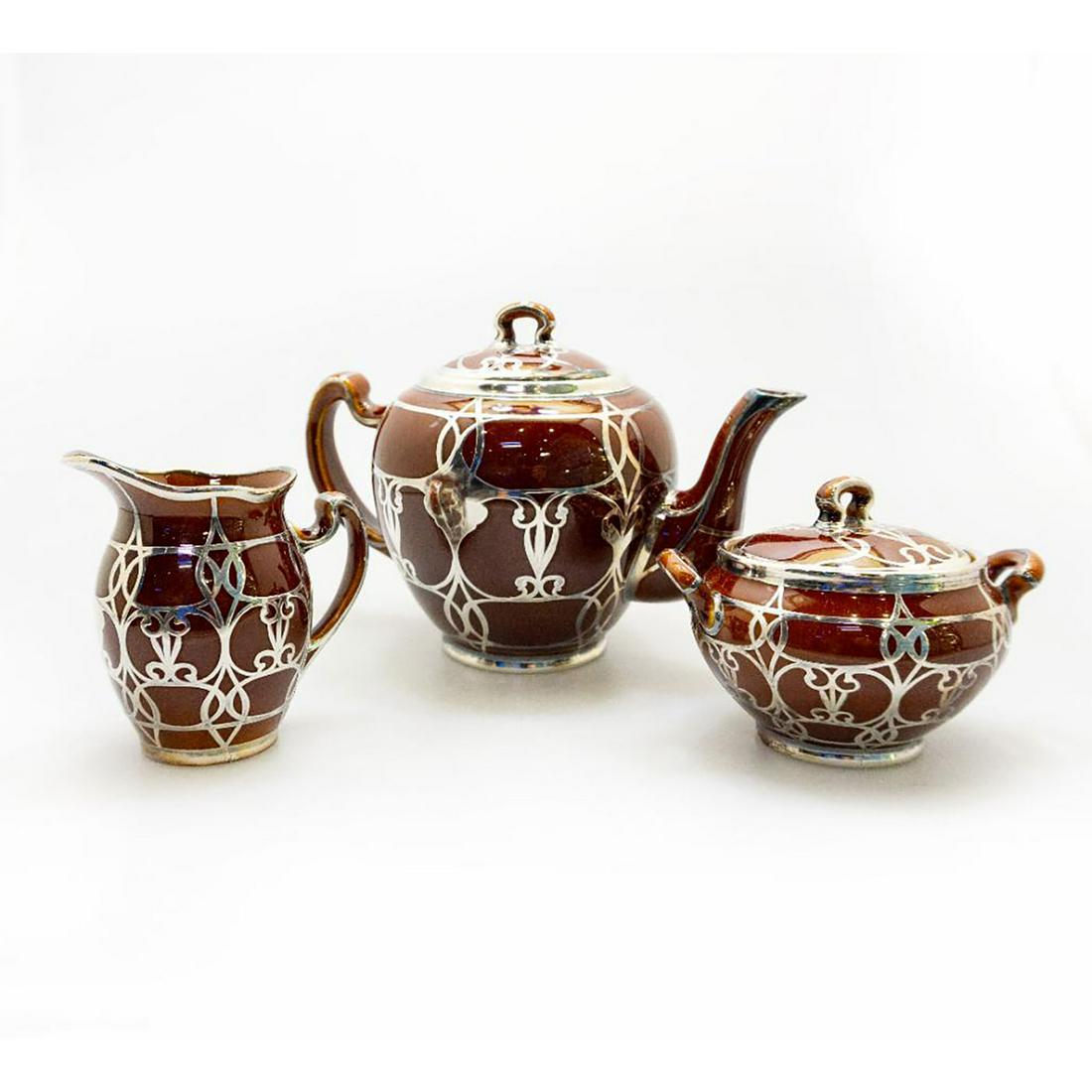 Lenox Porcelain Silver Overlaid Tea Set Of 3: Three-Piece Lenox Porcelain Art Nouveau Silver Overlay Tea Set, early 20th century, comprising teapot, creamer, and covered sugar, the ovoid pots with brown glaze, with silver overlay. Marked on the b