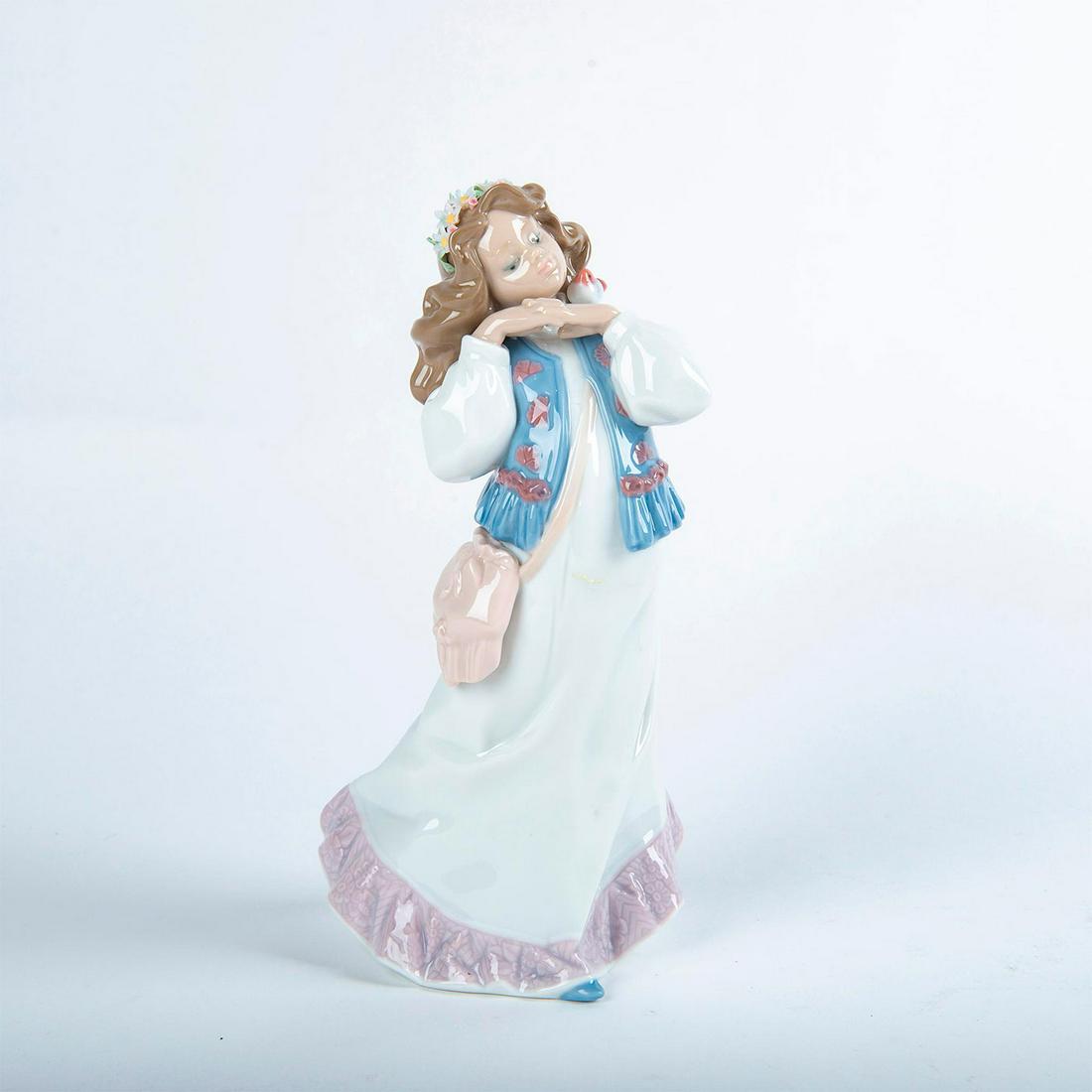 Lladro Porcelain Figurine, Dreams Of A Summer Past: Glossy porcelain figurine; modeled girl in white dress with a blue vest and satchel. Lladro backstamp. Includes original box. Artist: Francisco Polope Issued: 1997 Dimensions: 9.75"H Country of Origin