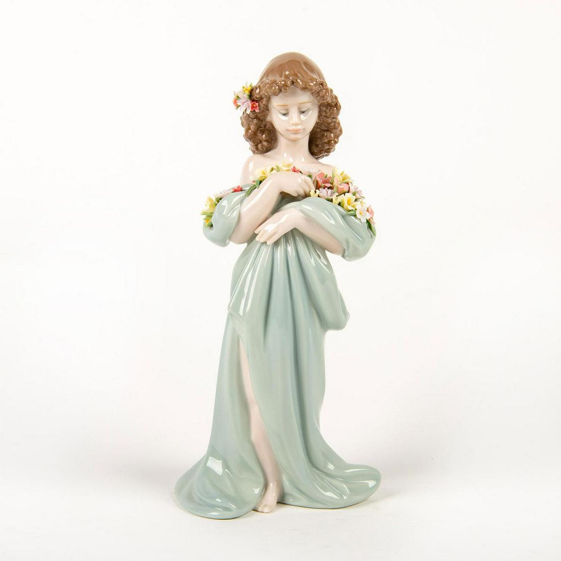 Lladro Porcelain Figurine, Petals Of Love 01006346: Glossy porcelain figurine of a girl cradling flowers in her pastel sage colored dress. Lladro backstamp. Does not include original box. Artist: Antonio Ramos Issued: 1998 Dimensions: 10"H Country of O