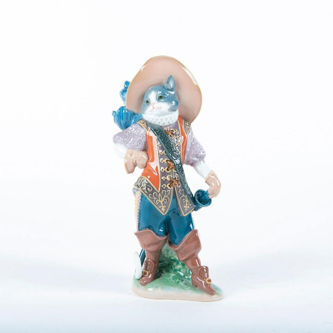 Lladro Porcelain Figurine; Puss In Boots 01008599: Glossy porcelain figure; Cat posing fully dressed. W. box. With Box Artist: Francisco Polope Issued: 2011 Dimensions: 8.75"H Country of Origin: Spain Manufacturer: Lladro