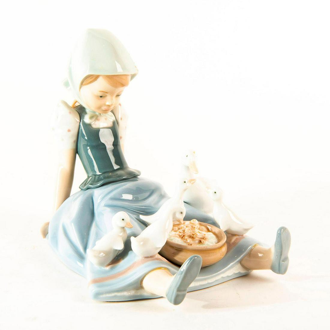 Girl, Saucepan and Duck 1980/1997 01005074 - Lladro: Glossy porcelain figurine of a girl with a family of ducklings on her lap, eating out of a pan. With original box. Lladro backstamp. Dimensions: 6.5"H