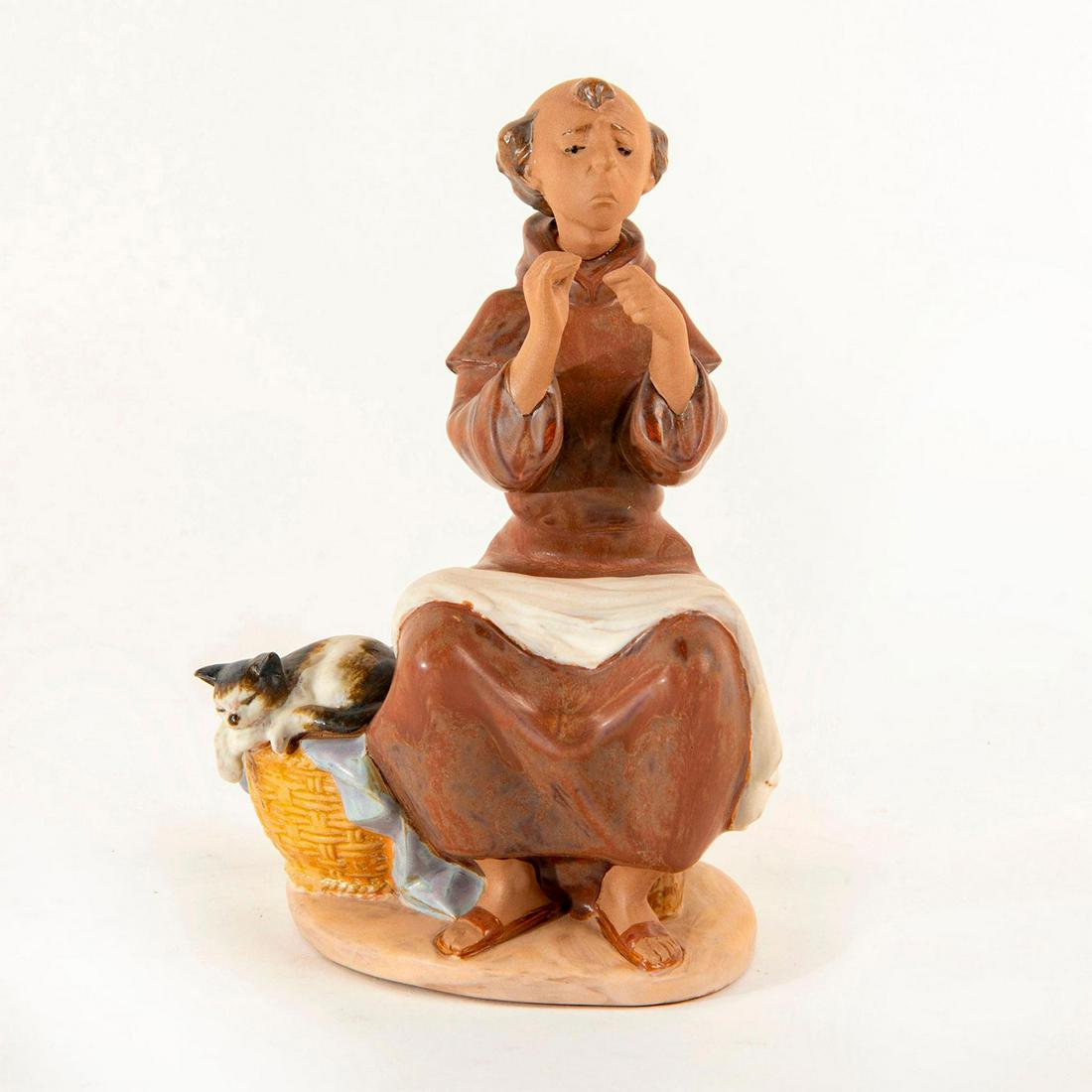 Prayerful Stitch 1990/1994 01012205 - Lladro Porcelain: Porcelain figurine with a Gres finish; Monk appears to fiddle around with a sewing needle while his cat rests by his side. With original box. Lladro backstamp. Dimensions: 7"H