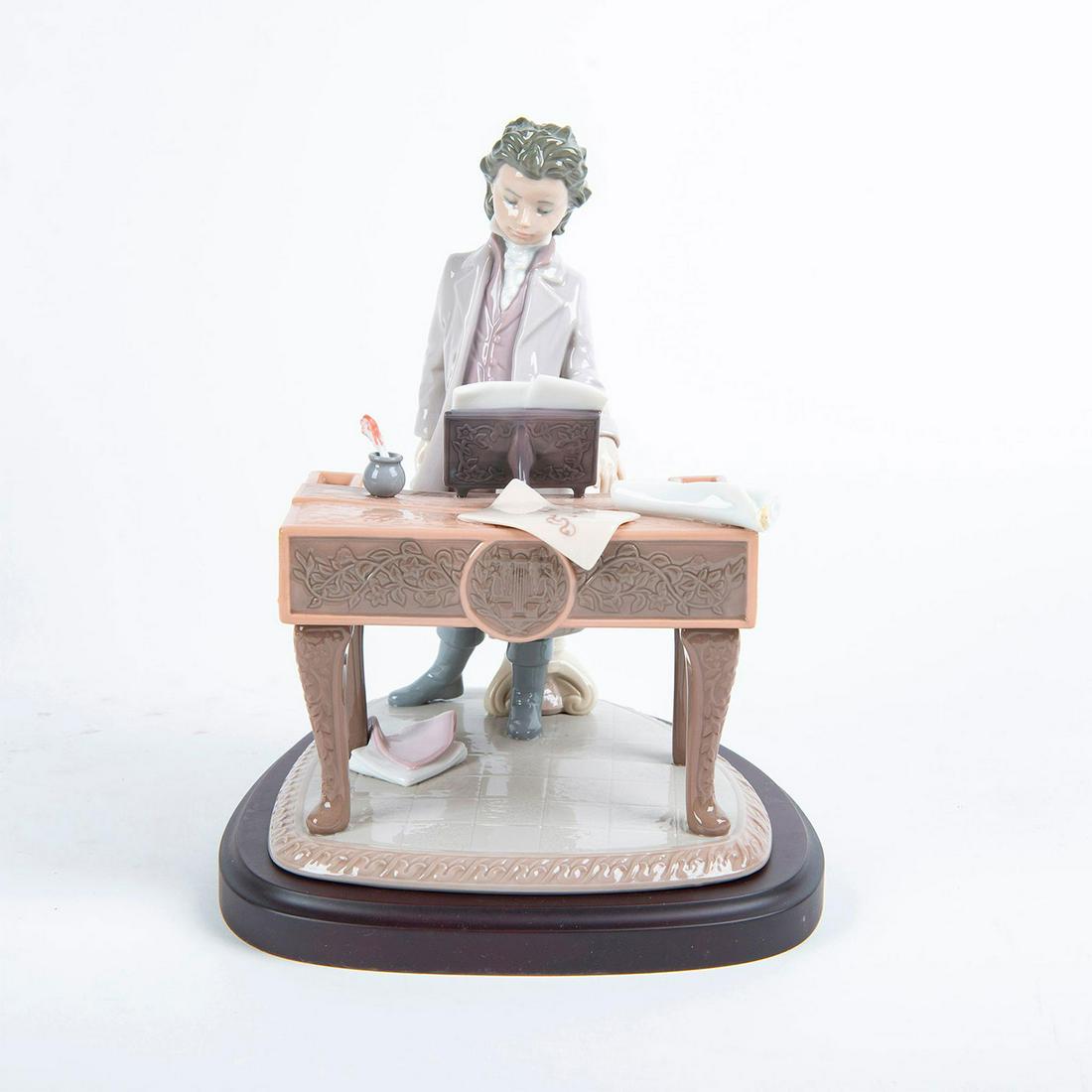 Young Beethoven 01001815 - Lladro Porcelain Figure: Glossy porcelain figurine depicting a young Beethoven, papers strewn around piano, composing a musical score. Limited edition #1176 of 2500. Lladro backstamp. Includes the original box and base. Limit