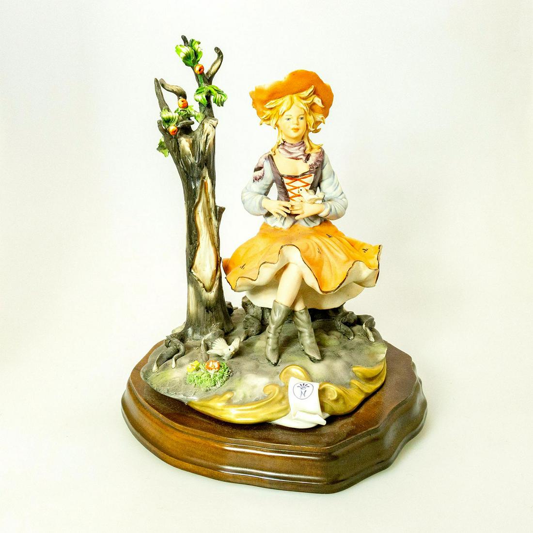 Capodimonte-Style Porcelain Figure, Provincial Lady +: A lady in a rustic hat and dress takes a rest with a bird perched on her hand and another at her feet. N with crown marking seen on base. Issued: 20th c. Dimensions: 12"H