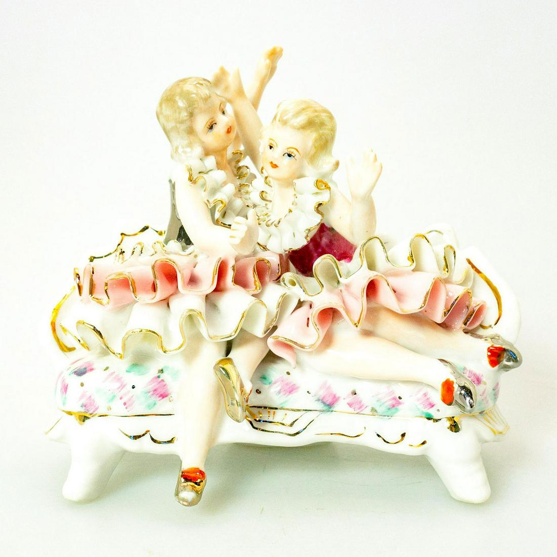 Vintage Bone China Figural Group, Twin Sisters: Victorian girls seated on a couch. Pink and white coloration; gilt accents. Hand painted; intricately detailed; ruffled design. Unmarked. Issued: 20th c. Dimensions: 5.25"H