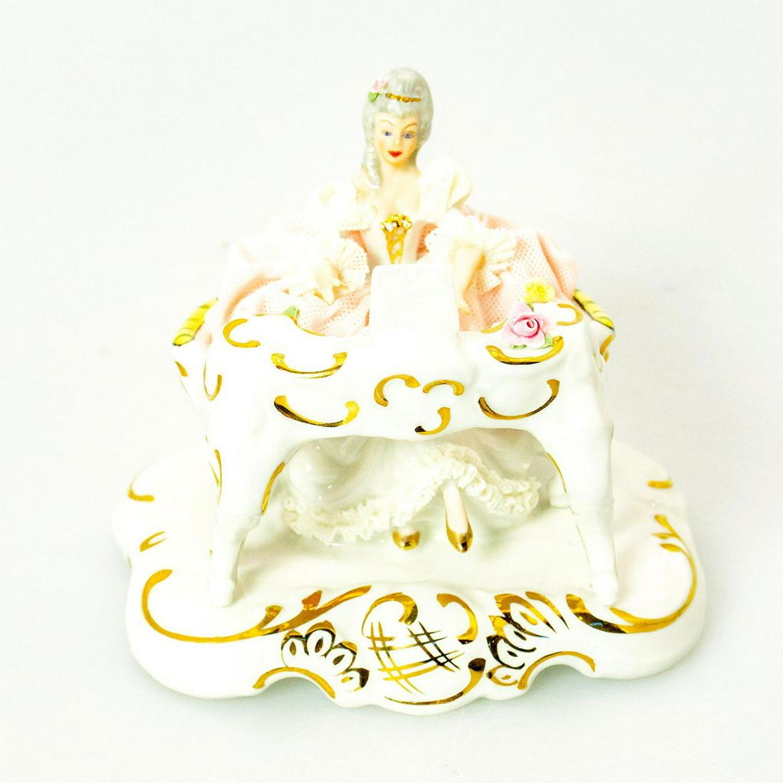 Vintage Dresden Figurine, Woman Playing Piano: Pink and white coloration; extensive lace detail; gilt highlights. Adorned with floral motifs. Dresden backstamp. Issued: 20th c. Dimensions: 4.5"H Manufacturer: Dresden Porcelain Country of Origin: G