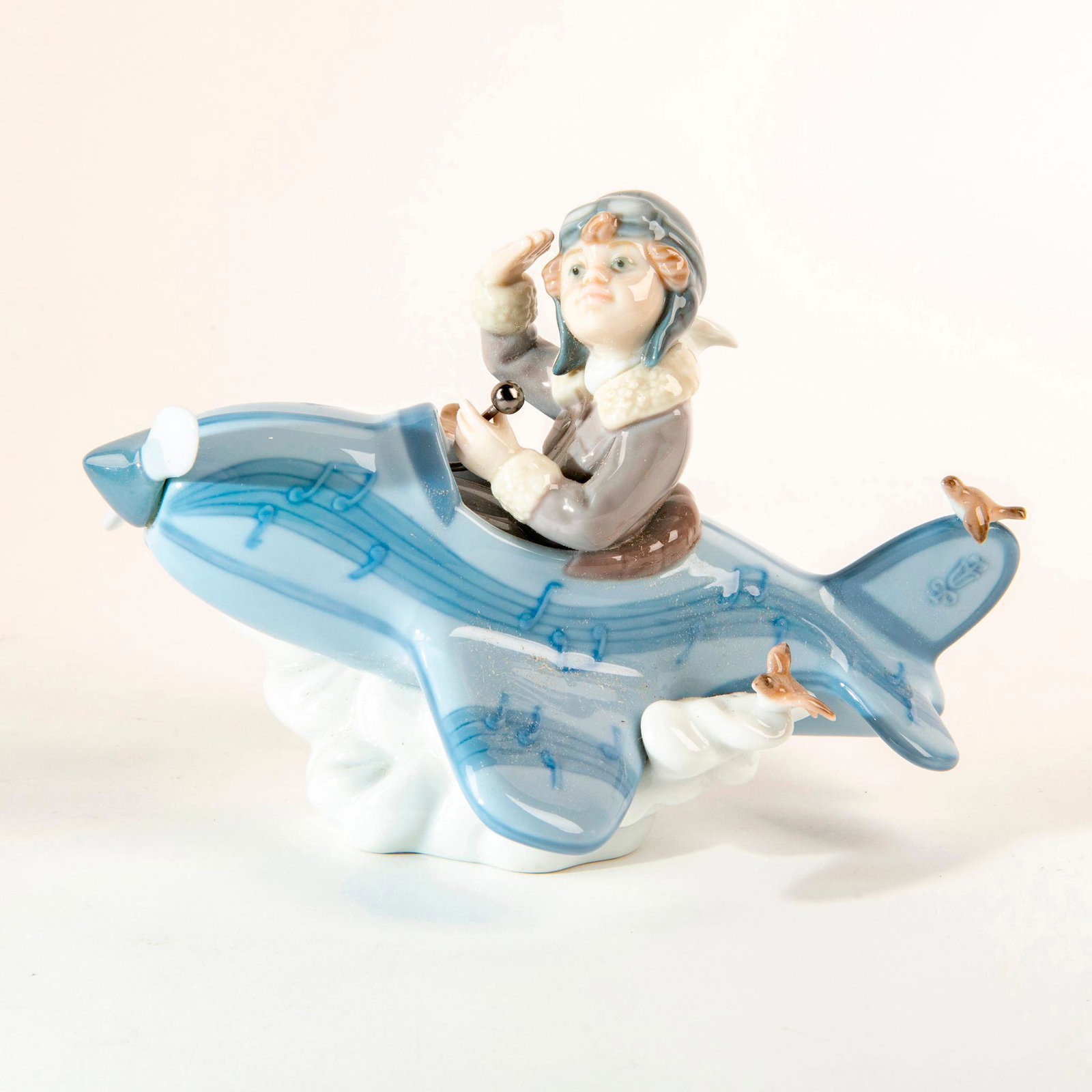 Over The Clouds 1005697 - Lladro Porcelain Figure: A plucky lad sits in his plane atop fluffy clouds. No box Issued: 1990 Dimensions: 5.5"H x 7.5"W Manufacturer: Lladro Country of Origin: Spain