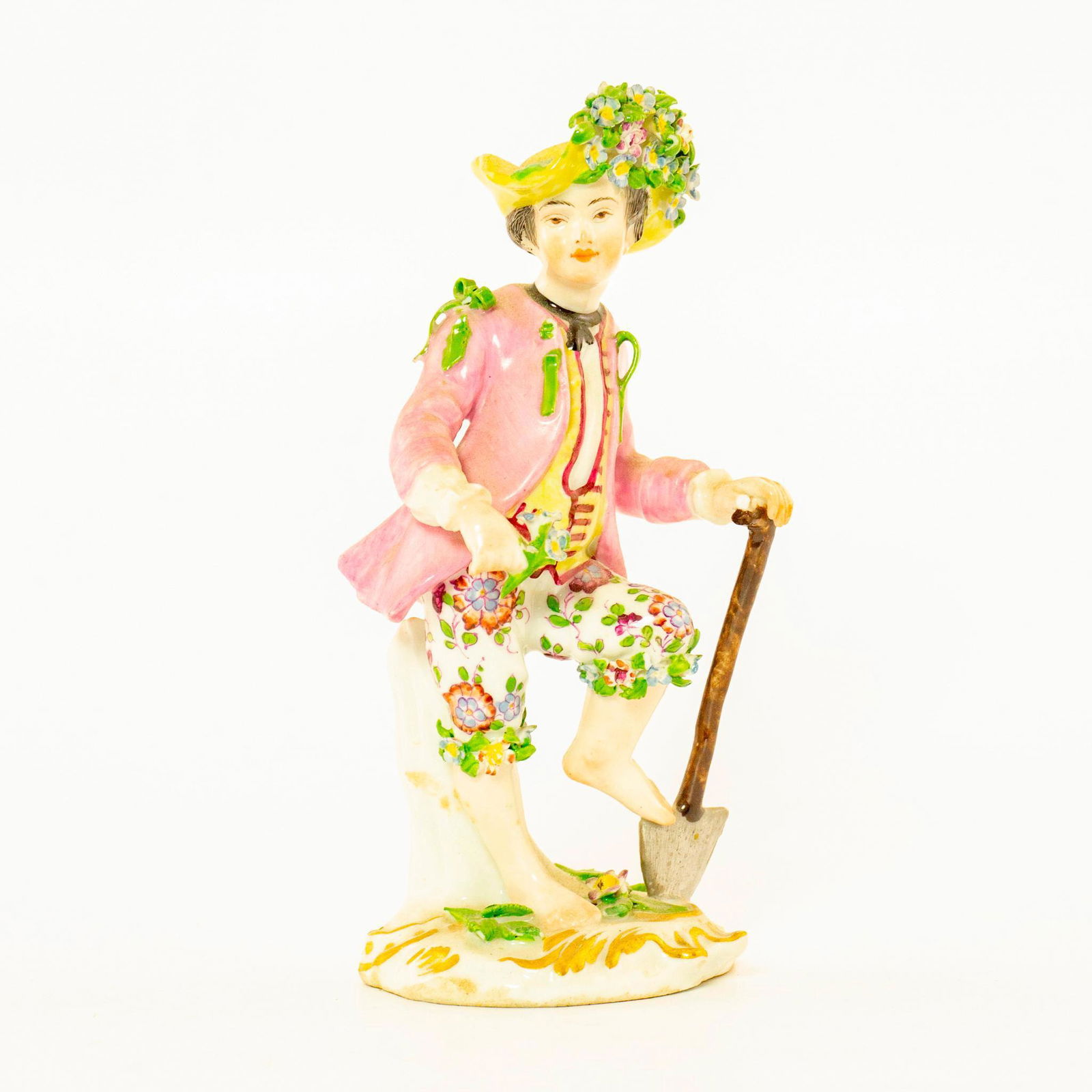 Vintage German Porcelain Figurine, Gardener: Boy with shovel. Pink and white coloration; gilt accents; intricate floral detail. Chips to petal. Issued: 20th c. Dimensions: 5.75"H Country of Origin: Germany