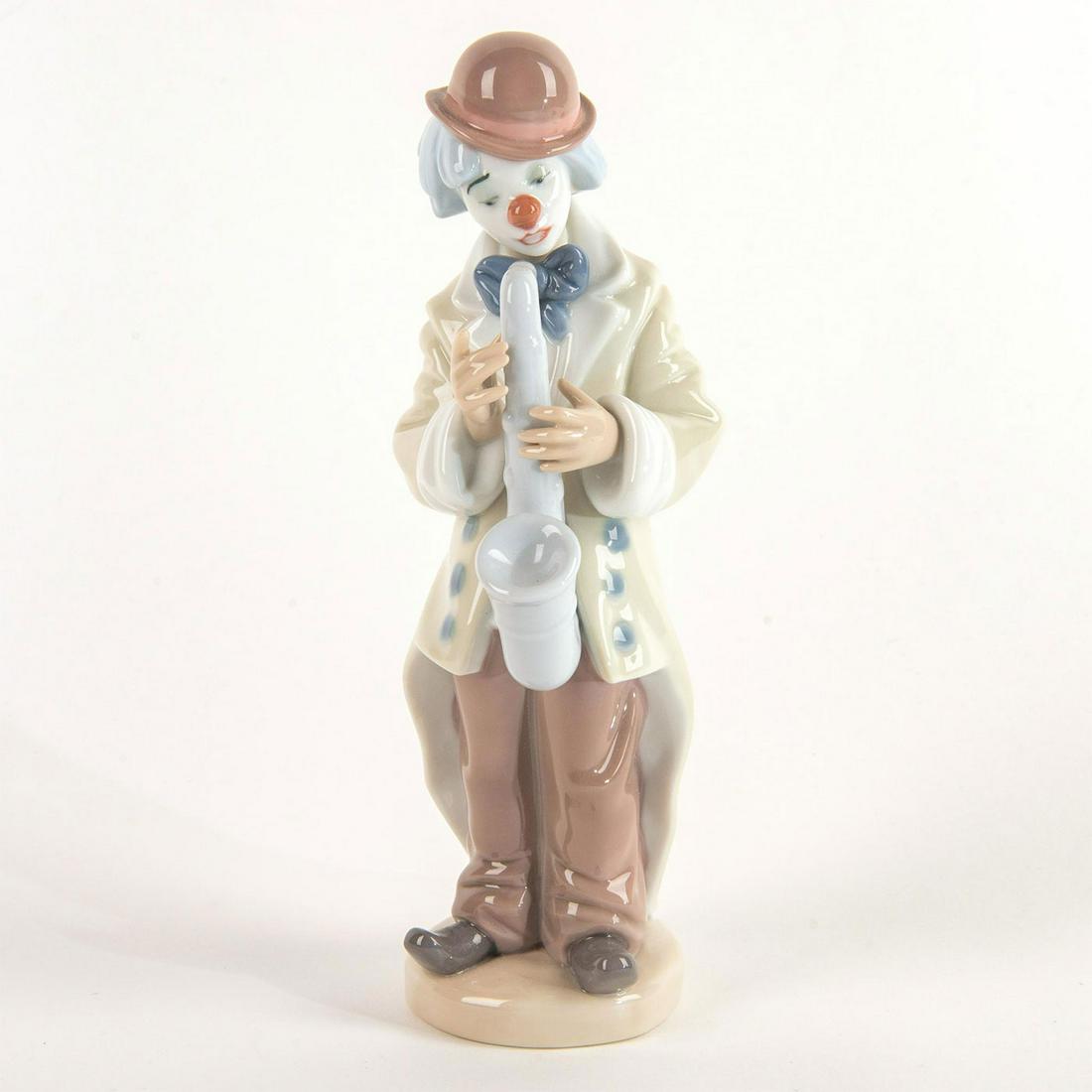Sad Sax 1005471 - Lladro Porcelain Figure: A sad clown stands taking a breath between playing his saxophone. No box Issued: 1988 Dimensions: 8.75"H x 2.75"W Manufacturer: Lladro Country of Origin: Spain