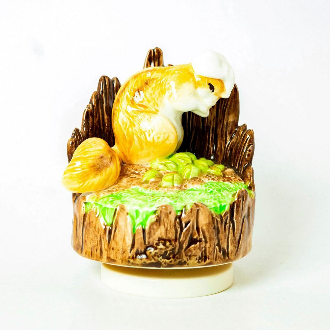 Schmid Music Box, Beatrix Potter, Chippy Hackee: Squirrel sitting within a molded wooden backing atop a grassy rotating base that plays music. Schmid backstamp. Original manufacture's label. Inscription on side reading 'Chippy Hackee, Schmid, Beatri