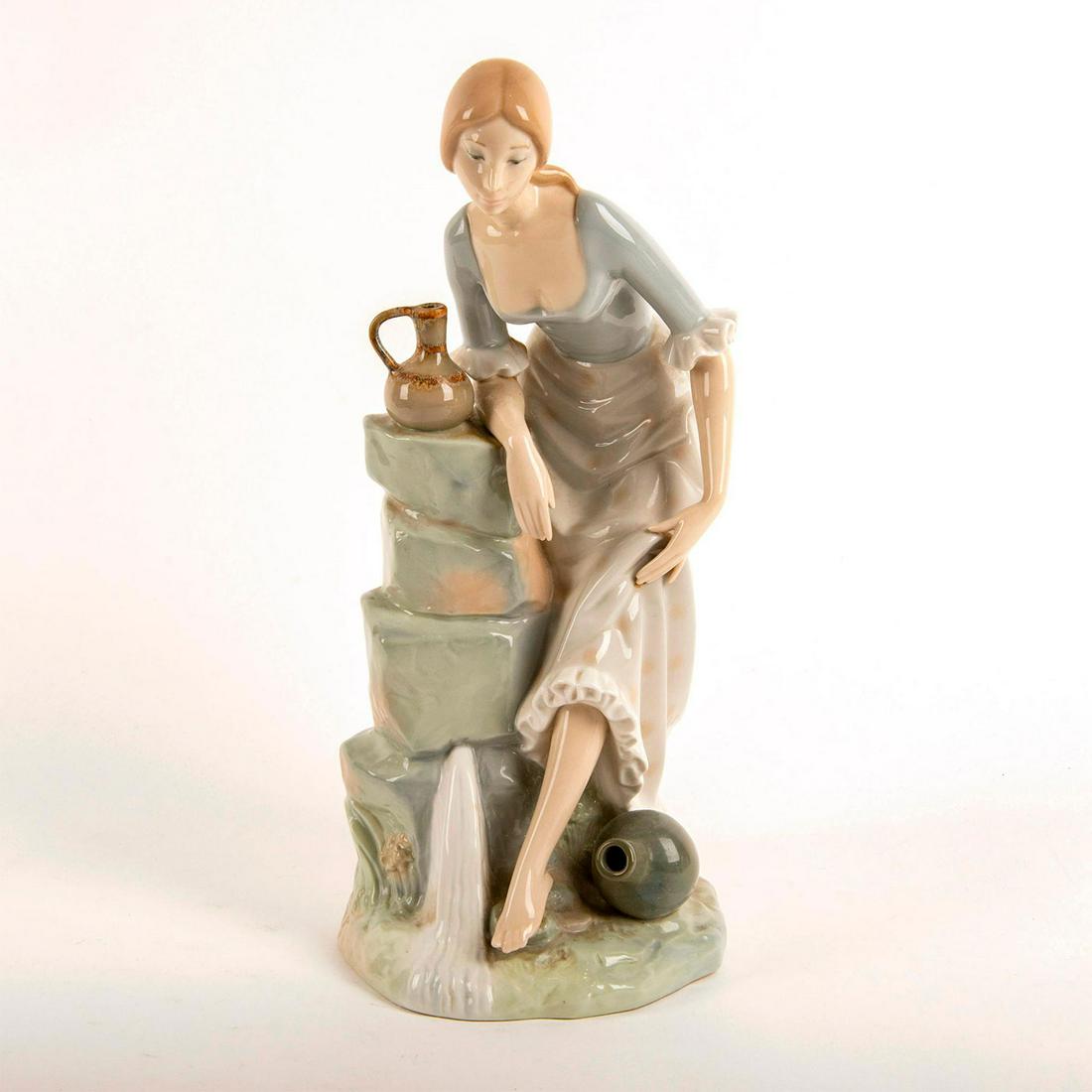 Girl from the Fountain 02010115 - Nao Porcelain Figure: Glossy porcelain figurine; Woman washing her feet in the stream. Does not include original box. Artist: Antonio Ruiz Issued: 1966 Dimensions: 13"H Manufacturer: Nao by Lladro Country of Origin: Spain