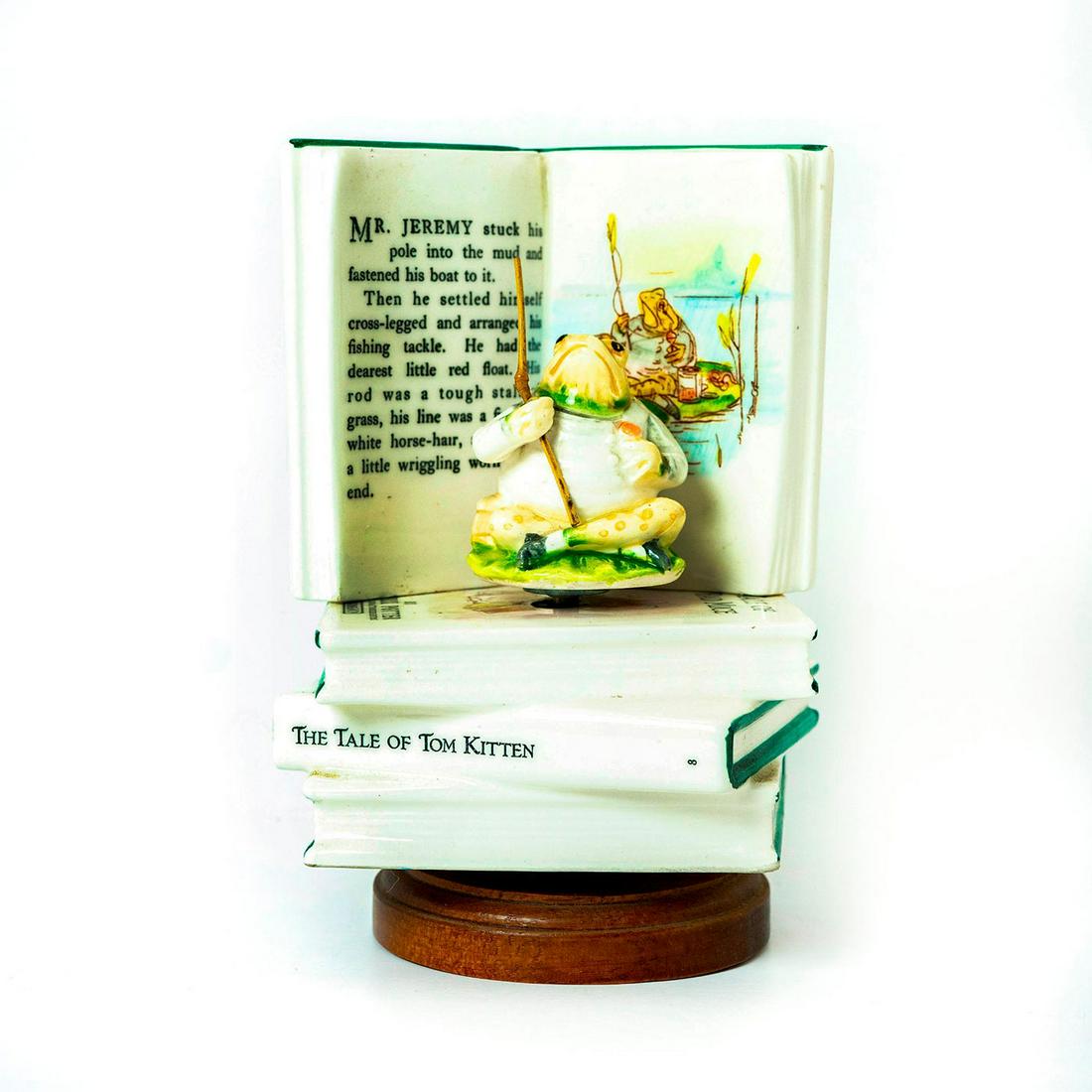 Schmid Music Box, Beatrix Potter, Mr. Jeremy Fisher: Frog sits atop a pile of book looking at an illustration of himself on the open page. Rotating musical base. Schmid backstamp. Original manufacture's label. Issued: 1985 Dimensions: 6.5"H Manufacturer
