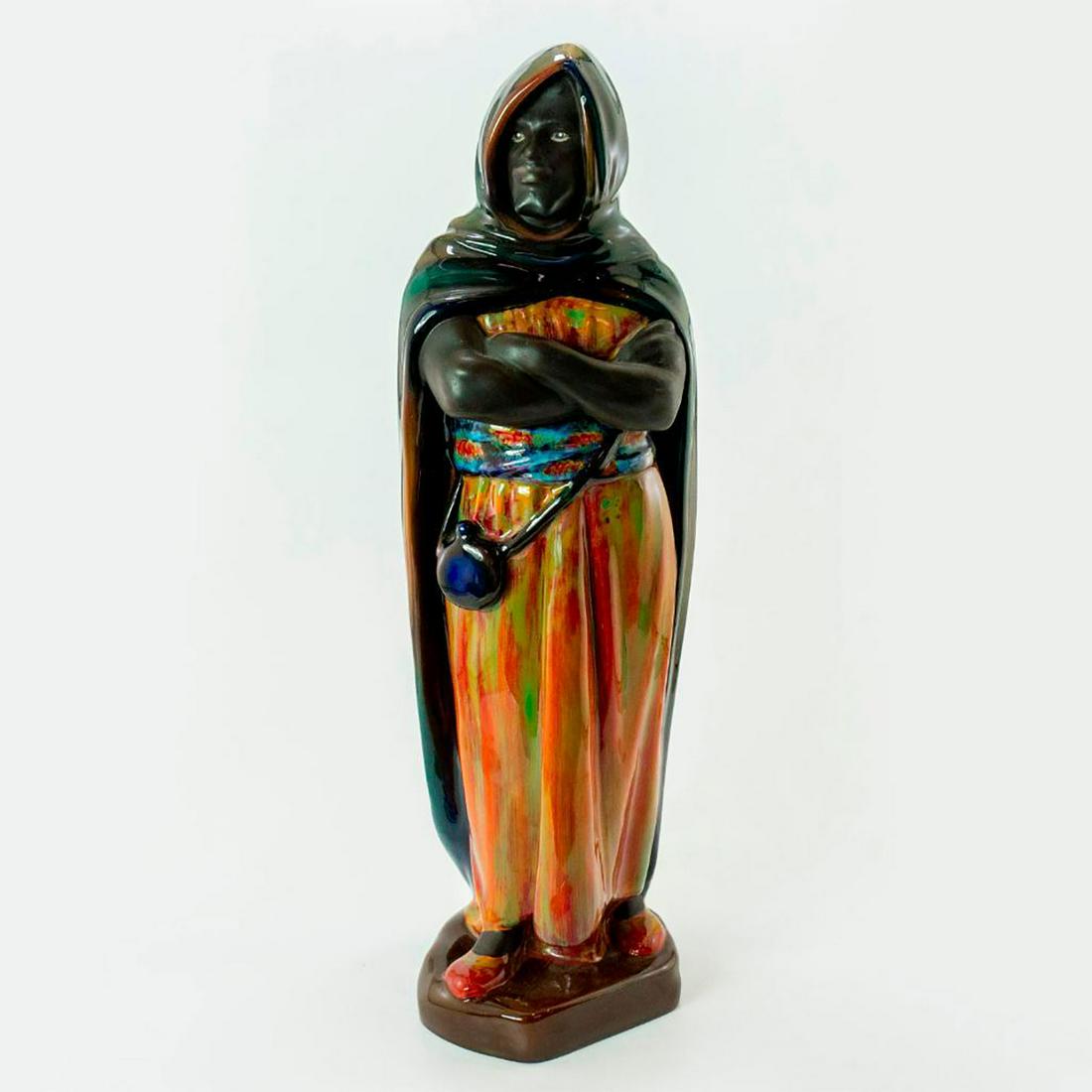 Large Royal Doulton Prestige Figurine, The Moor HN2082: Man stands in hooded cape with arms crossed. Glazed and matte; colors in oranges, blues and greens. Titled on base. Doulton backstamp. Artist: Charles Noke Issued: 20th c. Dimensions: 16.5"H Manufactu