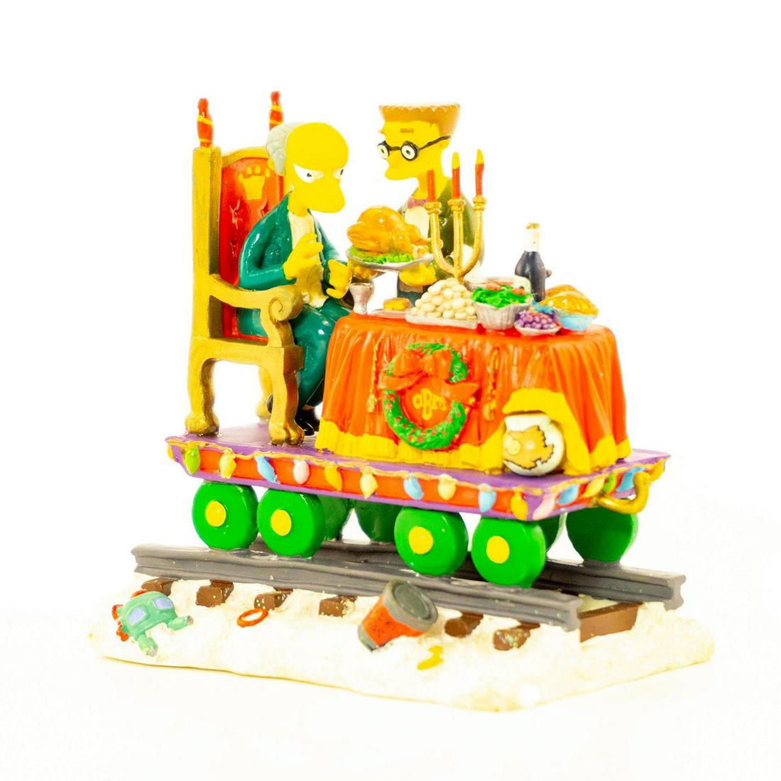 The Simpsons - A Feast For One Figurine: Matte finished figurine; Thanksgiving feast being served to Simpsons character; on train tracks. Box included. Issued: 2003 Dimensions: 3"H Manufacturer: Hamilton Collection Country of Origin: China