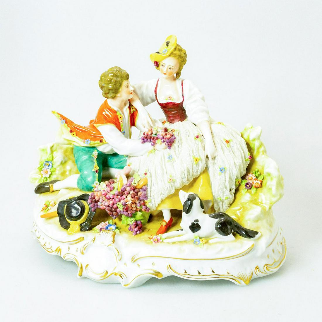 Capodimonte Porcelain Figurine, Courting Couple: Glazed; Man in orange and woman in lace; sitting in colorful, garden scene. Dog near feet. Chipped/Broken lace on back and front of dress. Numbered to bottom base. Issued: 19th c. Dimensions: 11"W x 9