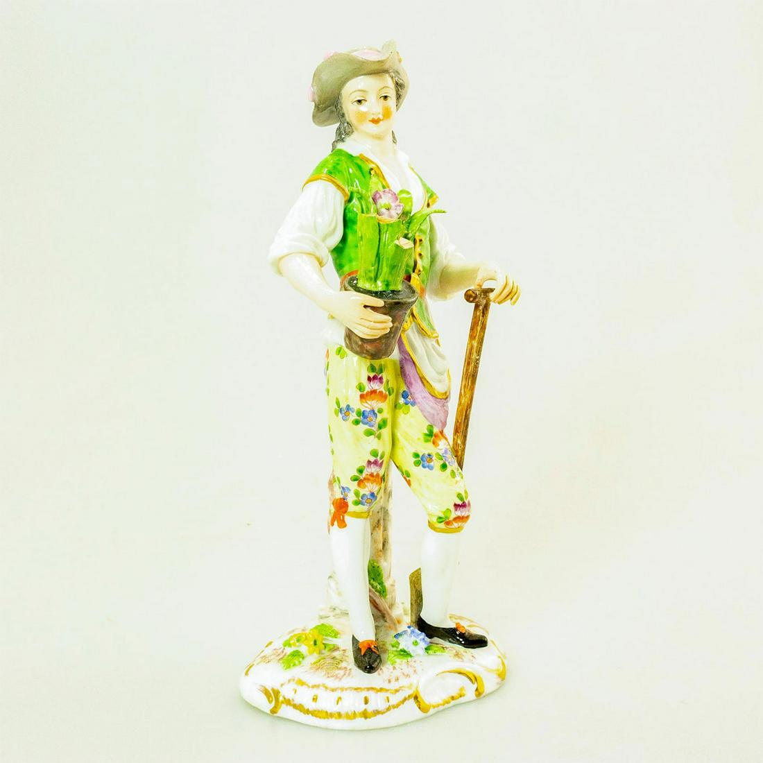 Meissen Style Porcelain Figurine Country Lad: Glossy porcelain figurine. Green top with white undershirt. Floral Pants. Broken leaves on the potted plant. Issued: 20th c. Dimensions: 8"H Country of Origin: Germany