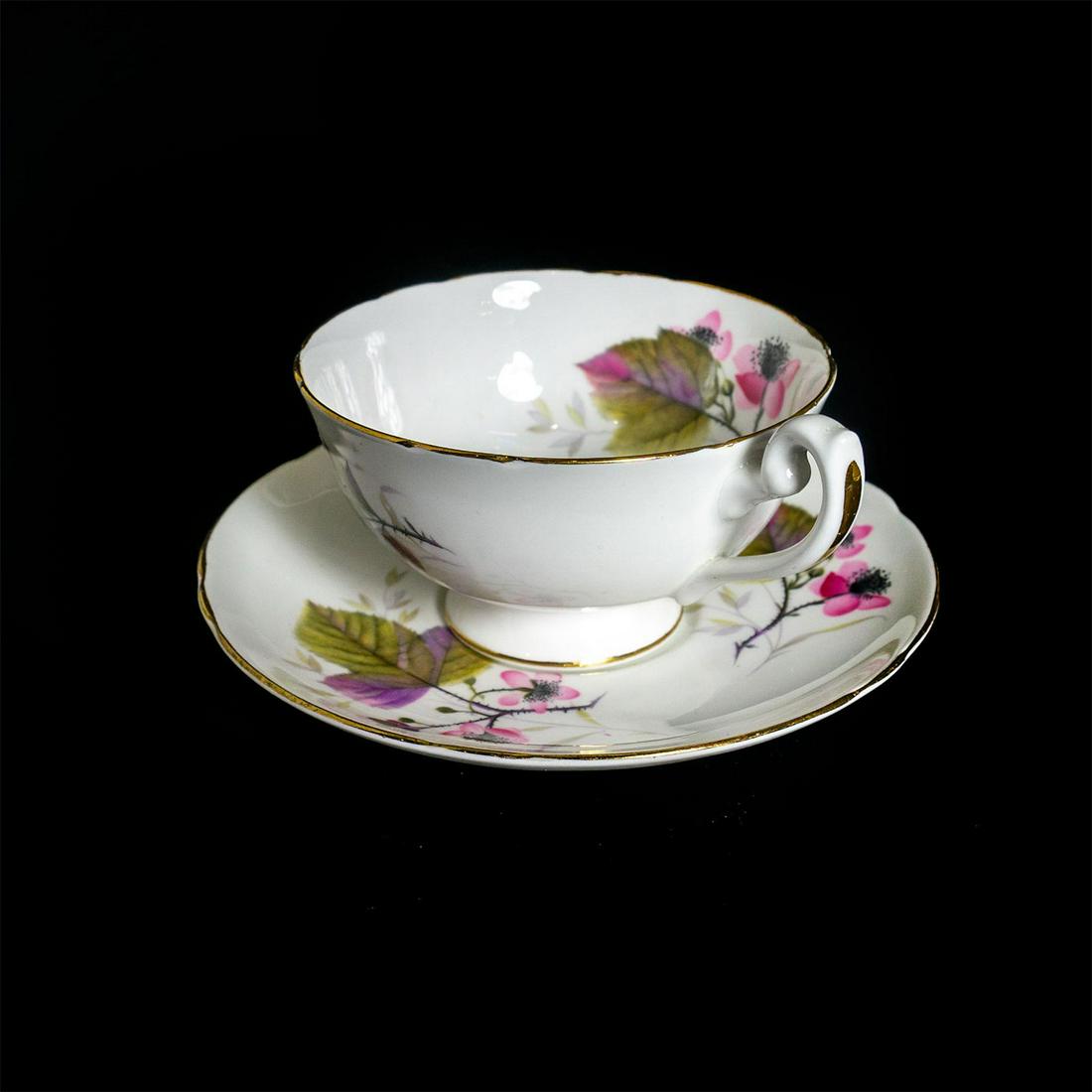 Shelley Fine Bone China Cup And Saucer: Fine china; painted leaves and pink floral pattern; gilt accents. Shelley backstamp. Issued: 20th c. Dimensions: 2.25"H x 5.75" dia. Manufacturer: Shelley China Country of Origin: England