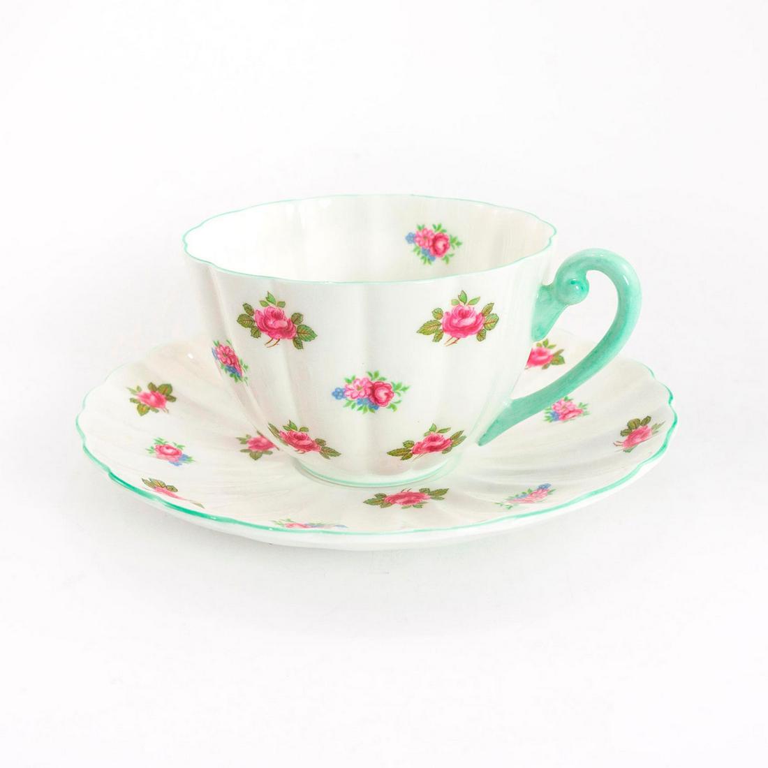 Shelley Fine Bone China Ludlow Cup And Saucer, Rosebud: Rosebud pattern; no. 13426. Glazed bone china cup and saucer, with pink and blue flora; green trim. Shelley backstamp. Issued: 20th c. Dimensions: 2.25"H x 5.5" dia. Manufacturer: Shelley China Countr