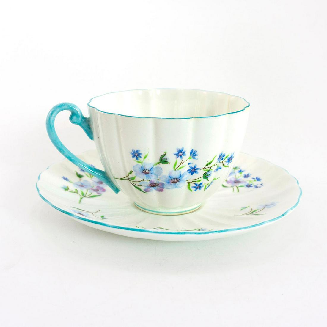 Shelley Fine Bone China Fluted Cup And Saucer, Blue: Blue Rock pattern; no. 13591. Glazed bone china cup and saucer, with blue flora; blue trim. Shelley backstamp. Issued: 20th c. Dimensions: 2.25"H x 5.5" dia. Manufacturer: Shelley China Country of Ori