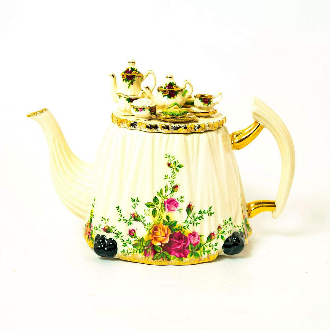 Royal Albert Earthenware Teapot Old Country Roses: Glossy Earthenware teapot from the Old Country Roses series. Fashioned as a white dress with flora wrapping the base. Gold gilt accents. Royal Albert backstamp. Issued: 1996 Dimensions: 7.5"H Manufact