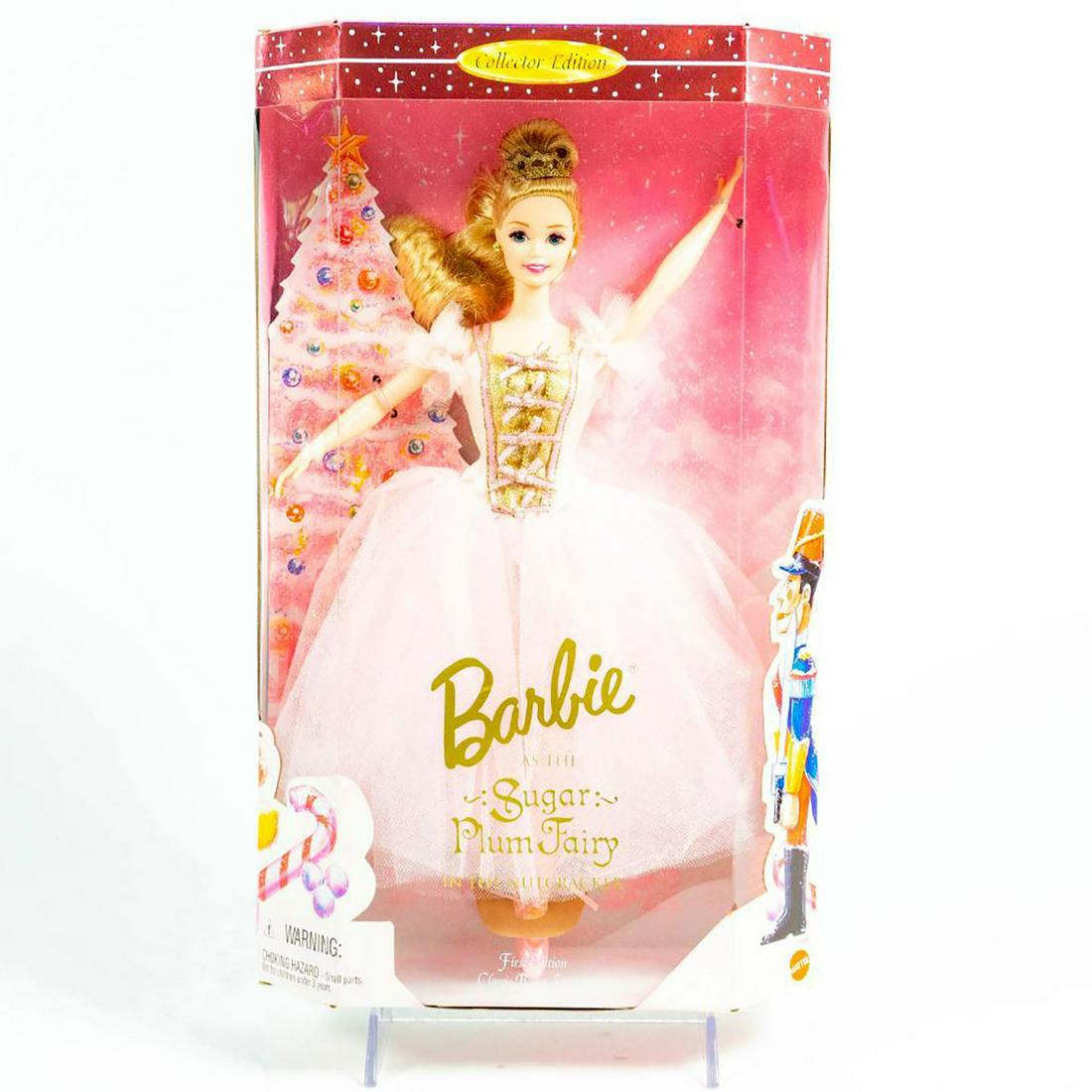 Mattel, Barbie As The Sugar Plum Fair In The Nutcracker: Barbie in beautiful pink mesh, fluffy dress with gold accents. With original box. SKU #17056. Issued: 1996 Dimensions: 13"H Manufacturer: Mattel Country of Origin: Malaysia