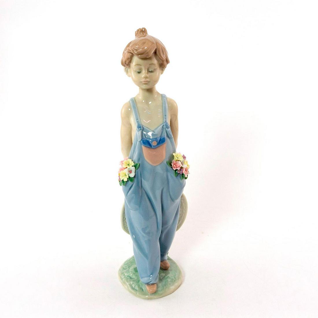 Pocket Full of Wishes 01007650 - Lladro Porcelain: Glossy; Boy in overalls with flowers in his pockets. With original box. Lladro backstamp. Artist: Antonio Ramos Issued: 1997 Dimensions: 10.25"H x 3.5"W Manufacturer: Lladro Country of Origin: Spain