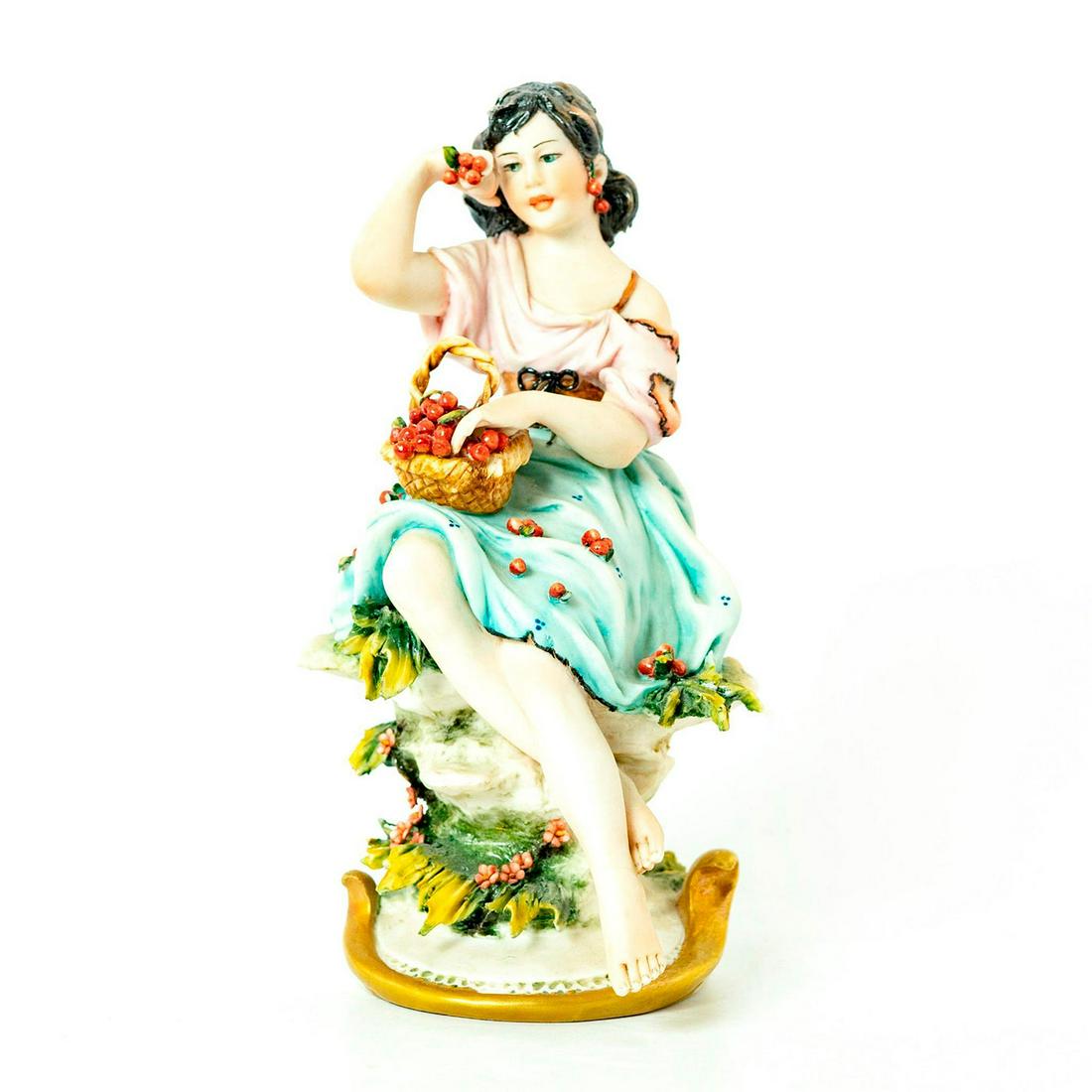 Capodimonte Luciano Cazzola Figurine, Girl With Berries: Matte; blue, pink and green coloration; gilt accents. Seated girl with basket of berries. Signed Cazzola on base. Capodimonte marks on base. Chips to leaves; hairline to feet, possible restoration. Ar