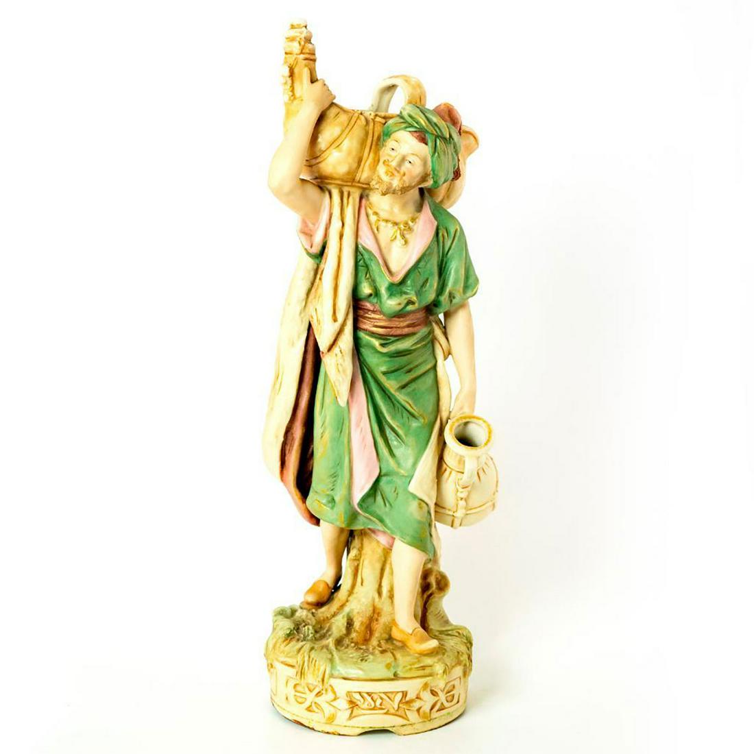 Royal Dux Bohemia Vellum Figurine, Water Carrier 1052: Highly-detailed and hand painted in pink and green coloration with hints of gold. Depicts a Middle Eastern man carrying water pitchers. On a circular stylized base. Impressed 1052 to bottom base. Roya