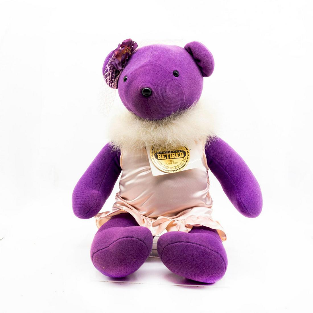 North American Bear Company Teddy Bear, Zsa Zsa Gabear: Purple plush, wearing a white dress with a puff collar and a lace hat. Original tag attached. Issued: 1982 Dimensions: 15"H Manufacturer: North American Bear Company Country of Origin: United States