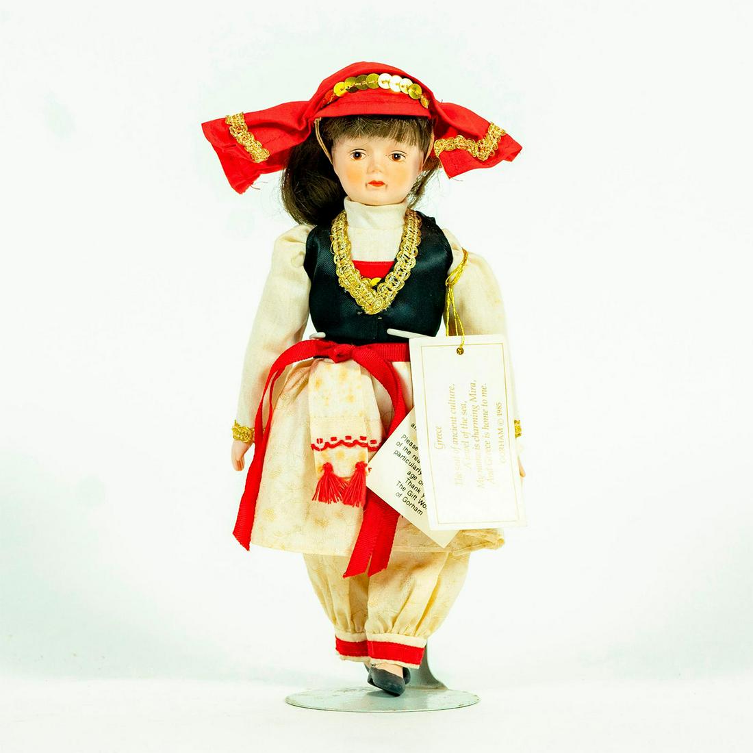 Vintage Doll, Gorham, Charming Mira: Collectible doll in embroidered patterned dress with red frill edging and bejeweled vest. Original label on right arm. Original warning label on right arm. Original tag under skirt. Attached to stand.