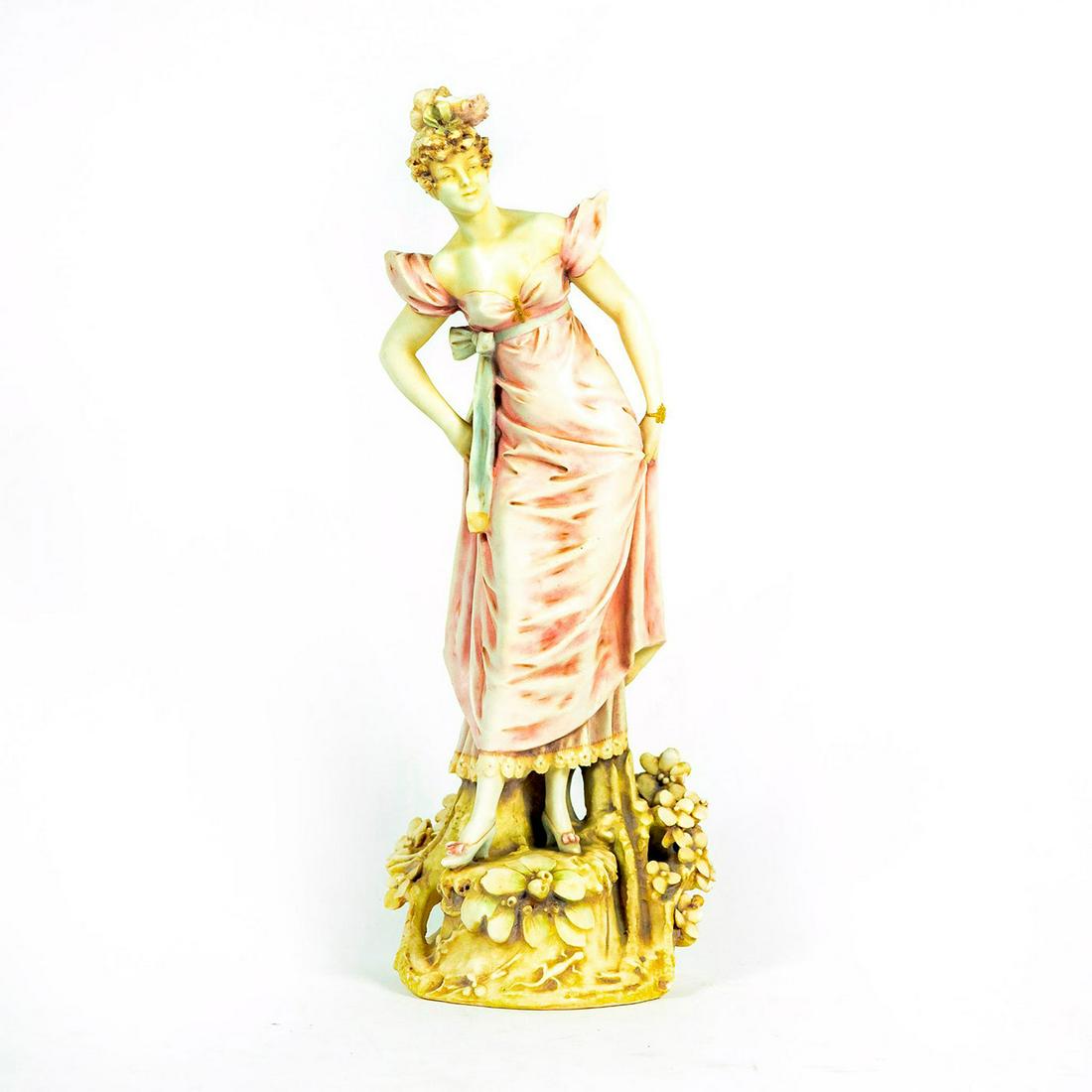 Guiseppe Armani Style Porcelain Figurine: Matte beige woman in light rose colored dress on a floral base. Gilded wristband. Unmarked. Broken hair piece and bow on dress. Missing flower petals on base. Dimensions: 15"H