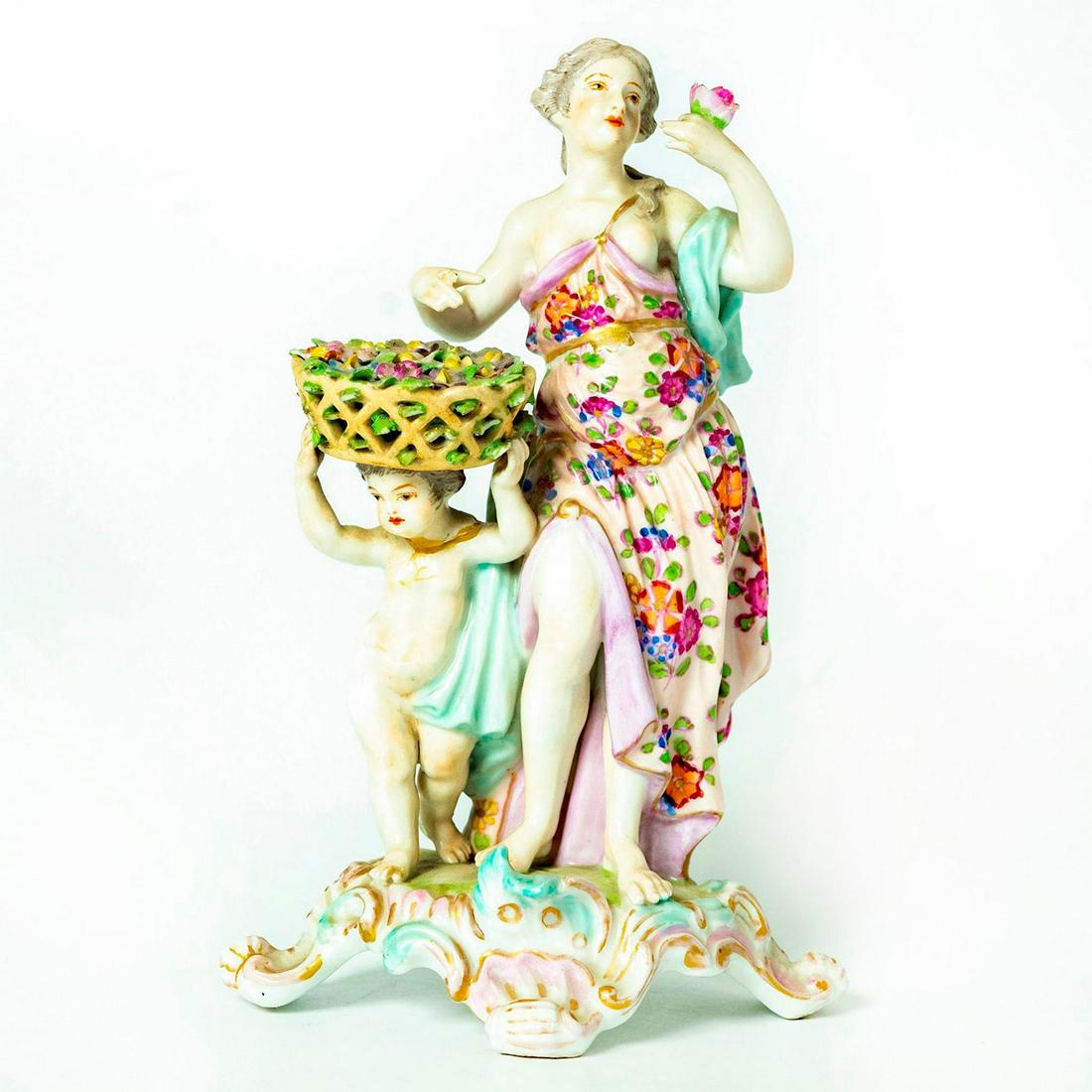Royal Vienna Porcelain Figurine: Woman in purple floral cloak and blue scarf holding a single rose and nude young child is balancing a flower basket on its head. Royal Vienna backstamp. Missing index finger tip and child's thumb. Iss