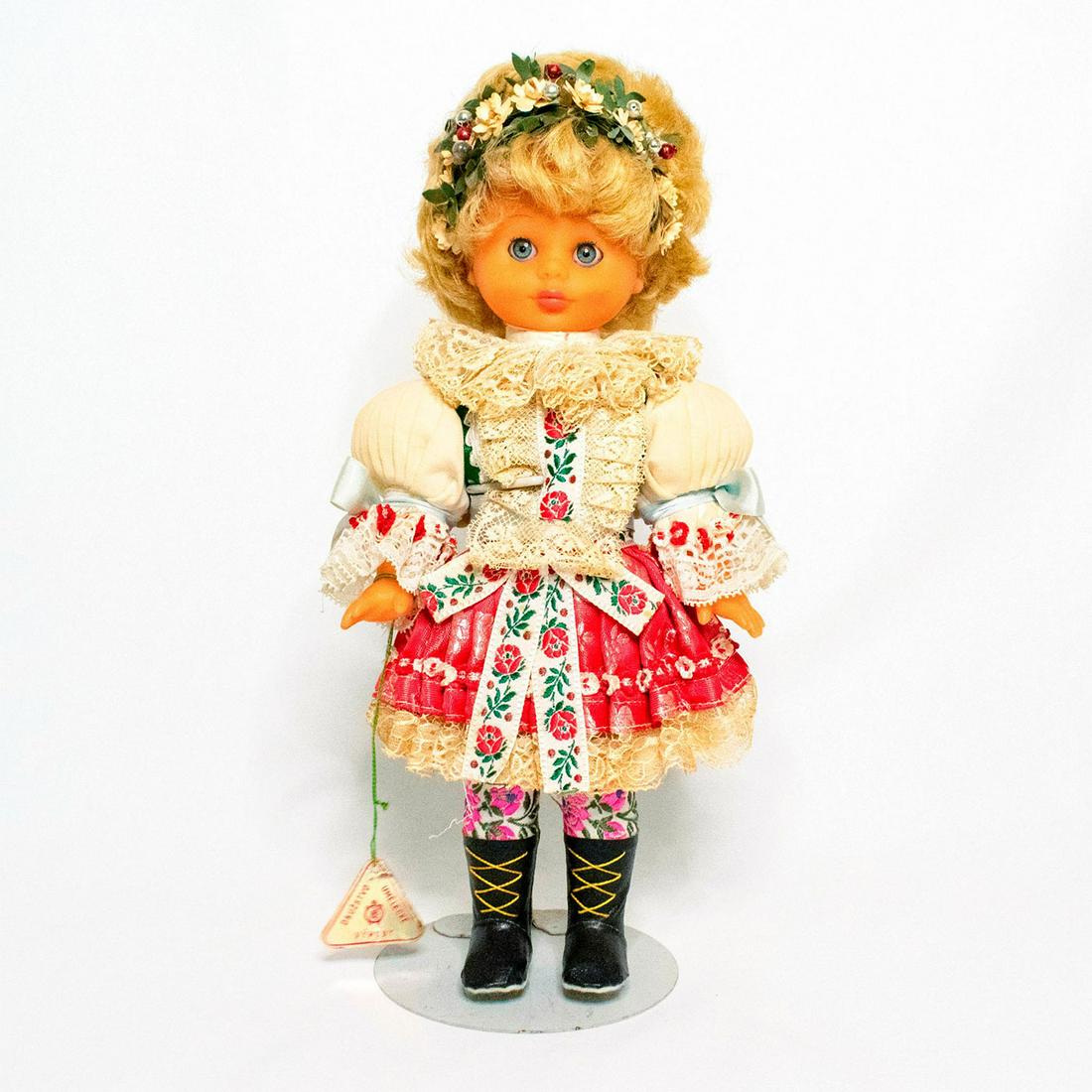 Lidova Tvorba Czechoslovakian Doll, Headband: Doll with blue eyes and blonde hair. Wearing a traditional costume from the Czech Republic. The outfit features puffed sleeves and a pleated skirt, with lace trim and collar. Doll wears floral embroid