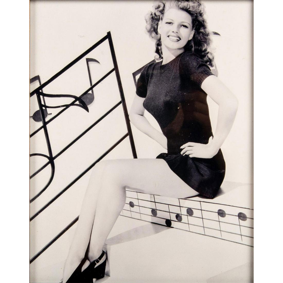 Framed Rita Hayworth Photograph: Black and white photo of Rita Hayworth surrounded by musical notes in the 1944 film Cover Girl. In a brown and bronze frame. Photo printed on Fujicolor Crystal Archive paper. Print date unknown. Easel