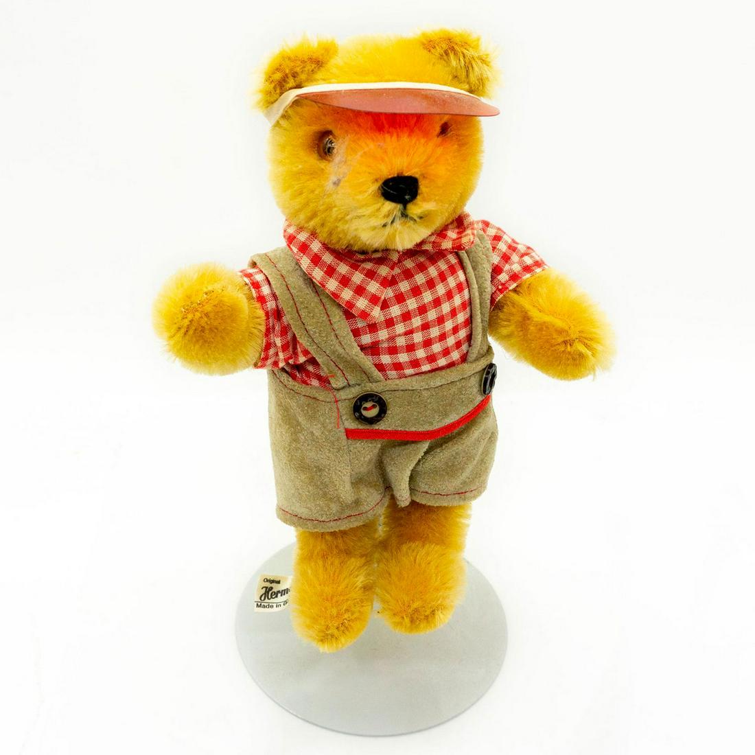 Hermann, Red and White Gingham Teddy Bear: Lovely caramel brown color teddy bear is wearing a white and red gingham shirt and beige colored suspender pants. Manufacture tag is attached to the foot. Shows some natural aging but in good overall 