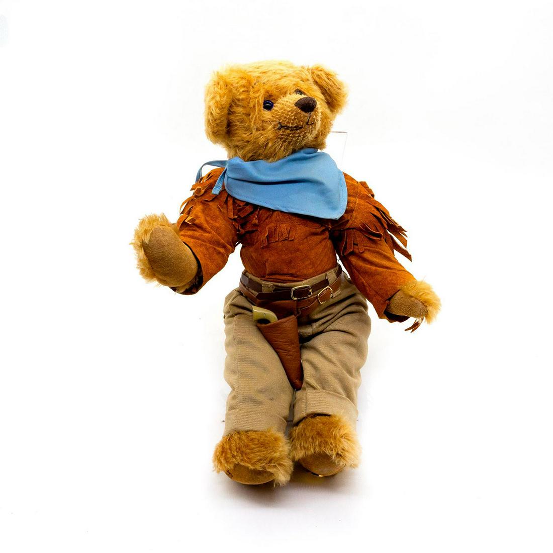 The Franklin Mint Teddy Bear, John Wayne: Triple jointed, mohair, glass eyes, shaved snout. Wearing a cowboy suit with a baby blue bandana. Around his hip is a gun holster with a revolver inside. Issued: 20th c. Dimensions: 15"H Manufacturer: