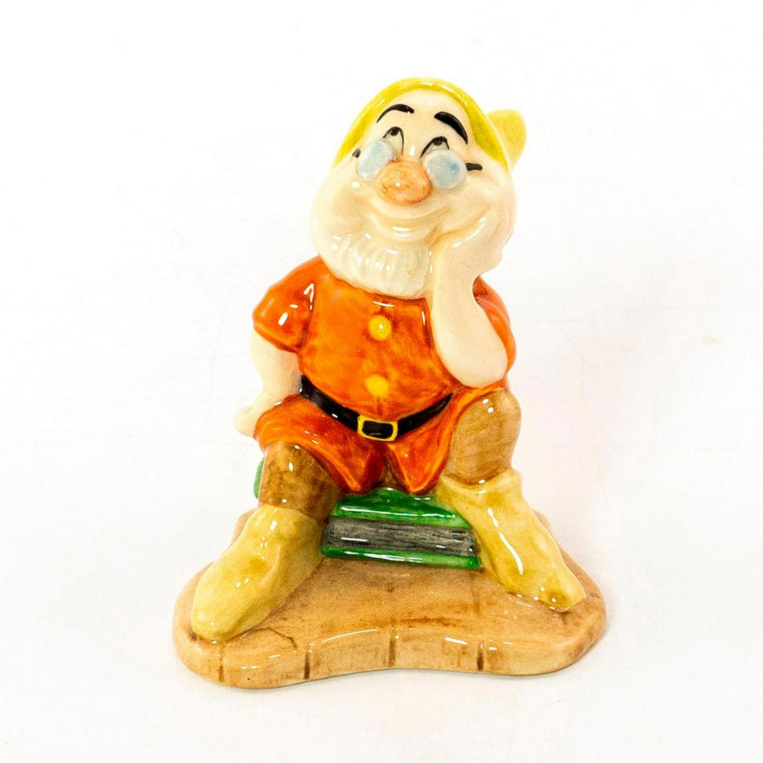 Royal Doulton Figurine, Snow White Doc, SW10: Walt Disney's Classic Snow White and Seven Dwarf's series. Doc is wearing orange top, brown pants, yellow hat and glasses. He is sitting on a green book. Backstamp on bottom. Comes in original box. Go