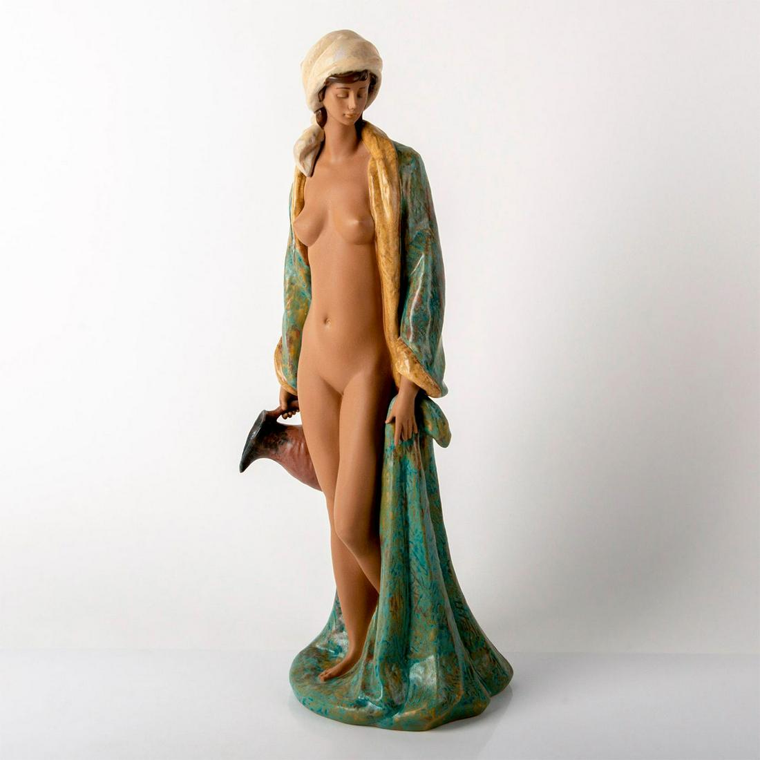 Early Awakening 1012369 - Lladro Porcelain Figurine: Gres finish; Nude woman wearing an open robe, holding a water pitcher. Lladro backstamp. Does not include the original box. Artist: Antonio Ramos Issued: 1998 - 2017 Dimensions: 22.5"H x 9.75"W Manufa