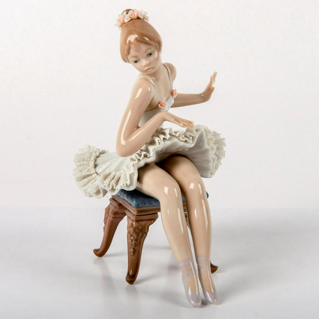 Recital 1005496 - Lladro Porcelain Figurine: Beautiful ballerina sitting on a blue foot stool, designed with white lace skirt and tiny pink flower details. Comes with original box. Lladro backstamp. Missing flower petals. Minor missing lace edge