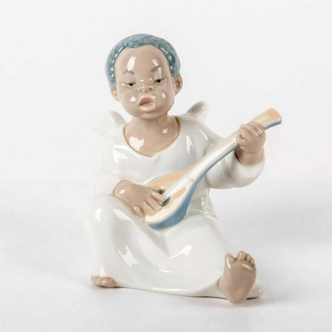Angel 1004537 - Lladro Porcelain Figurine: Glossy finish; An angel sits singing and playing his mandolin. Lladro backstamp. Does not include the original box. Artist: Fulgencio Garcia Issued: 1970 Dimensions: 4.75"H x 4.75"W Manufacturer: Llad