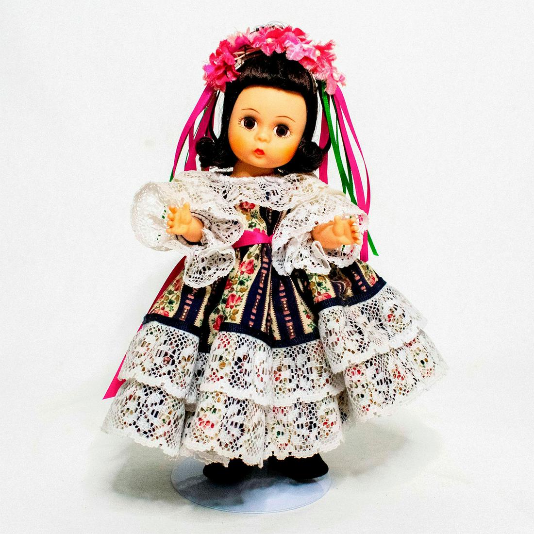 Madame Alexander Doll, Czechoslovakia: Doll with brown eyes and dark hair. She wears a floral patterned dress with lace ruffled trim, sleeves, and collar. She has a petticoat beneath her skirt, with lace-trimmed pantaloons, socks, black sh
