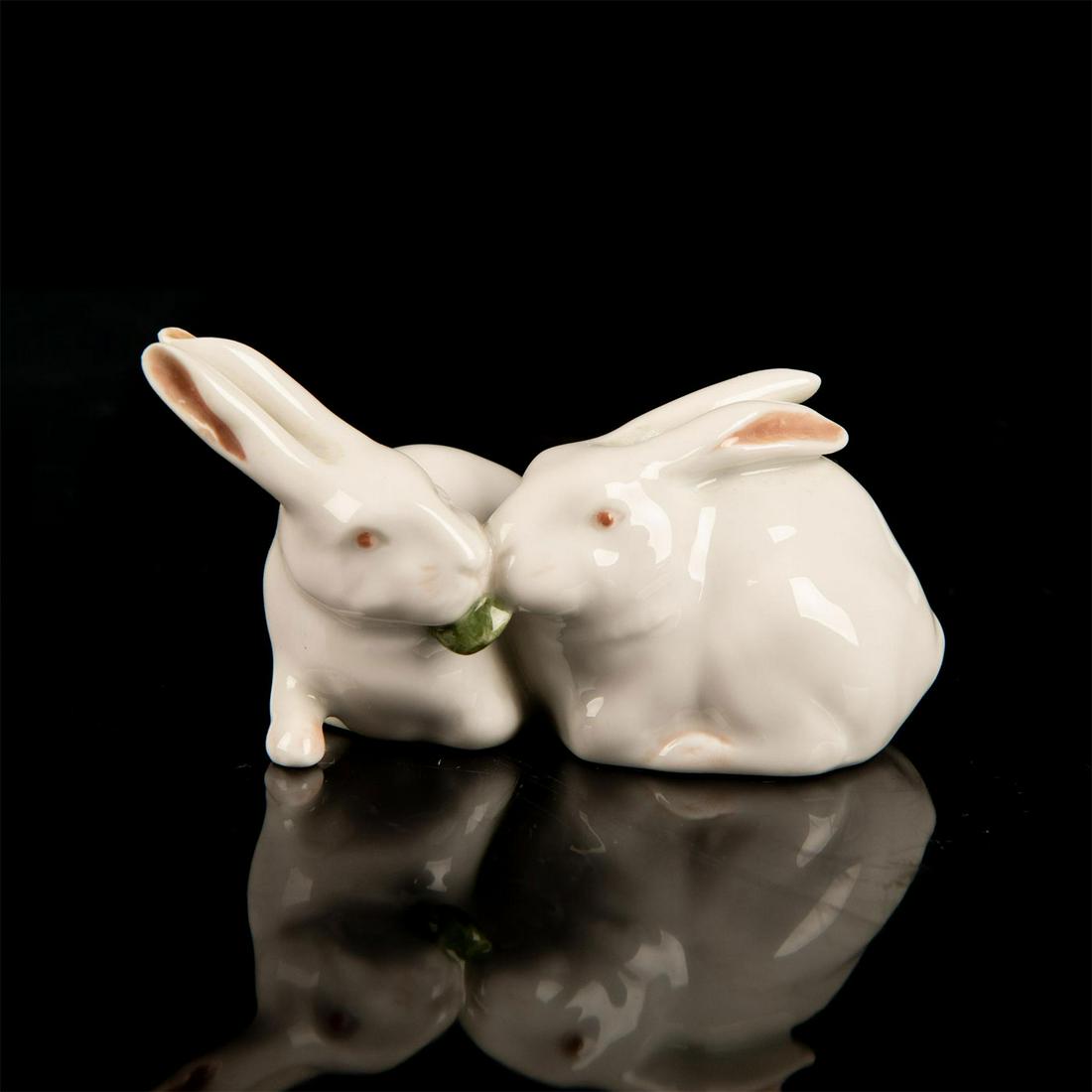 Royal Copenhagen Porcelain Figurine, Pair of Rabbits: Figurine of a pair of white rabbits eating leafy green. White and red coloration. Royal Copenhagen backstamp. Good condition. #rabbit #hare Issued: 20th c. Dimensions: 4.25"W x 2.25"H Manufacturer: Ro